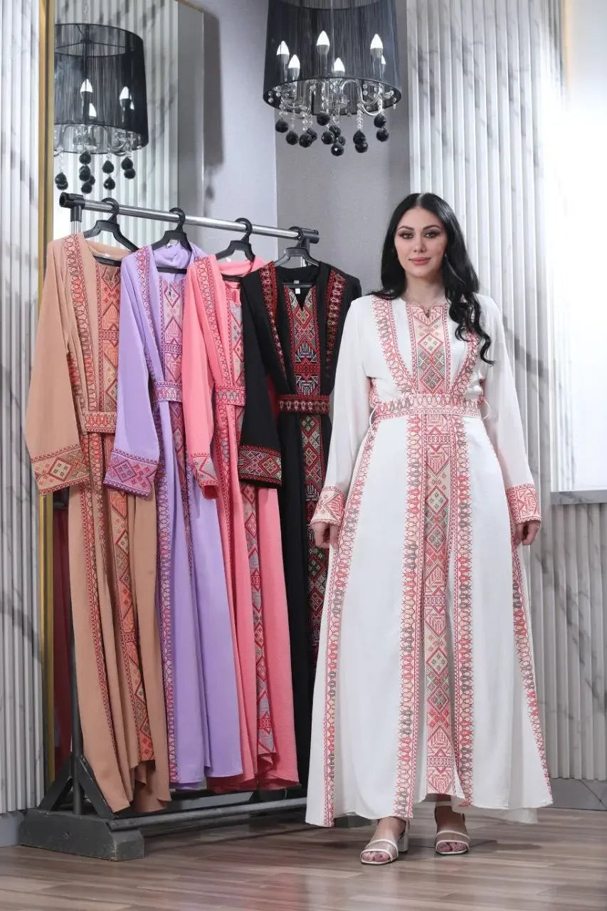 Embroidered abaya for women by Palestinian Elegance in white with traditional patterns displayed with similar abayas in various colors