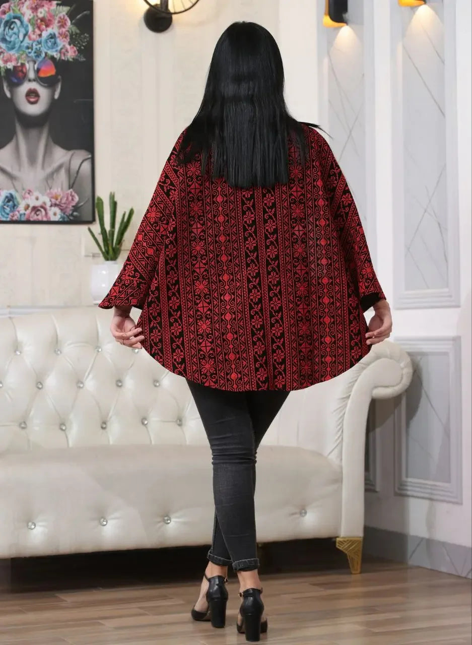 Back view of woman wearing a red and black embroidered cape jacket with traditional Palestinian designs