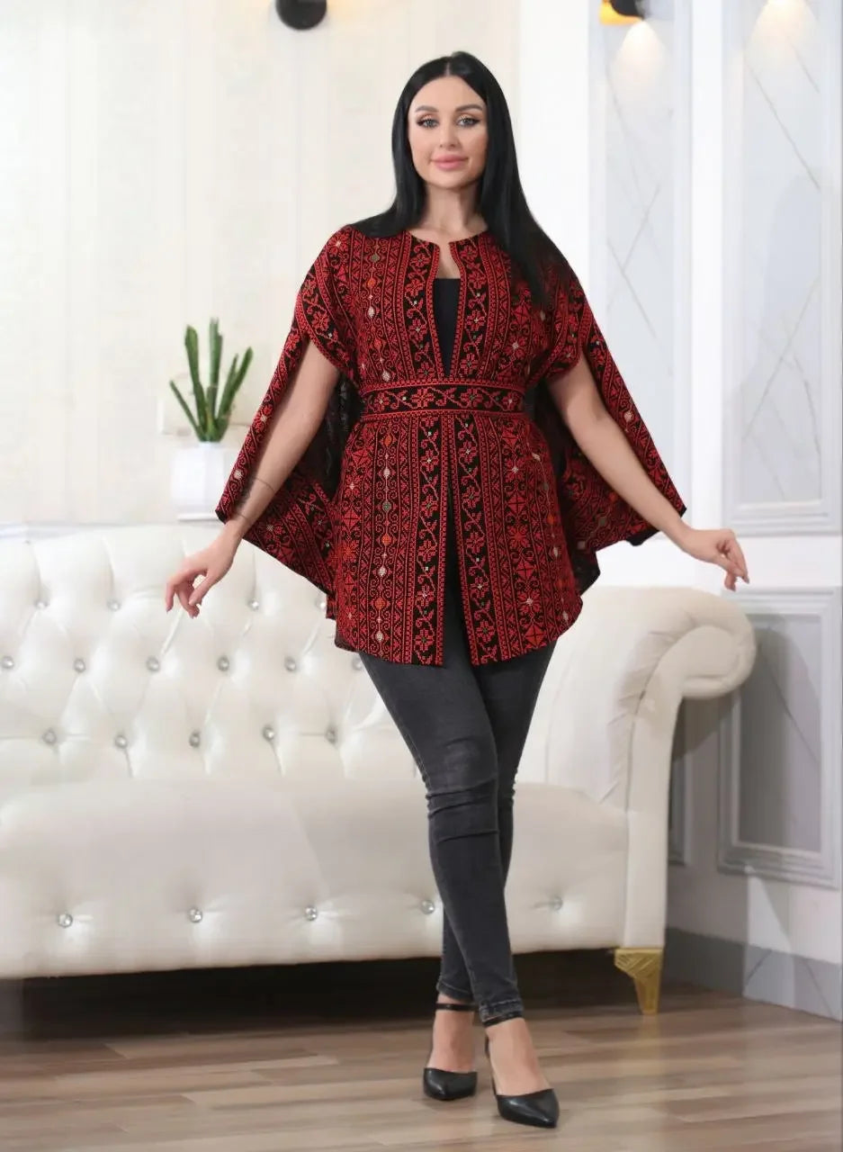 Palestinian Elegance embroidered cape jacket in red and black worn by woman indoors
