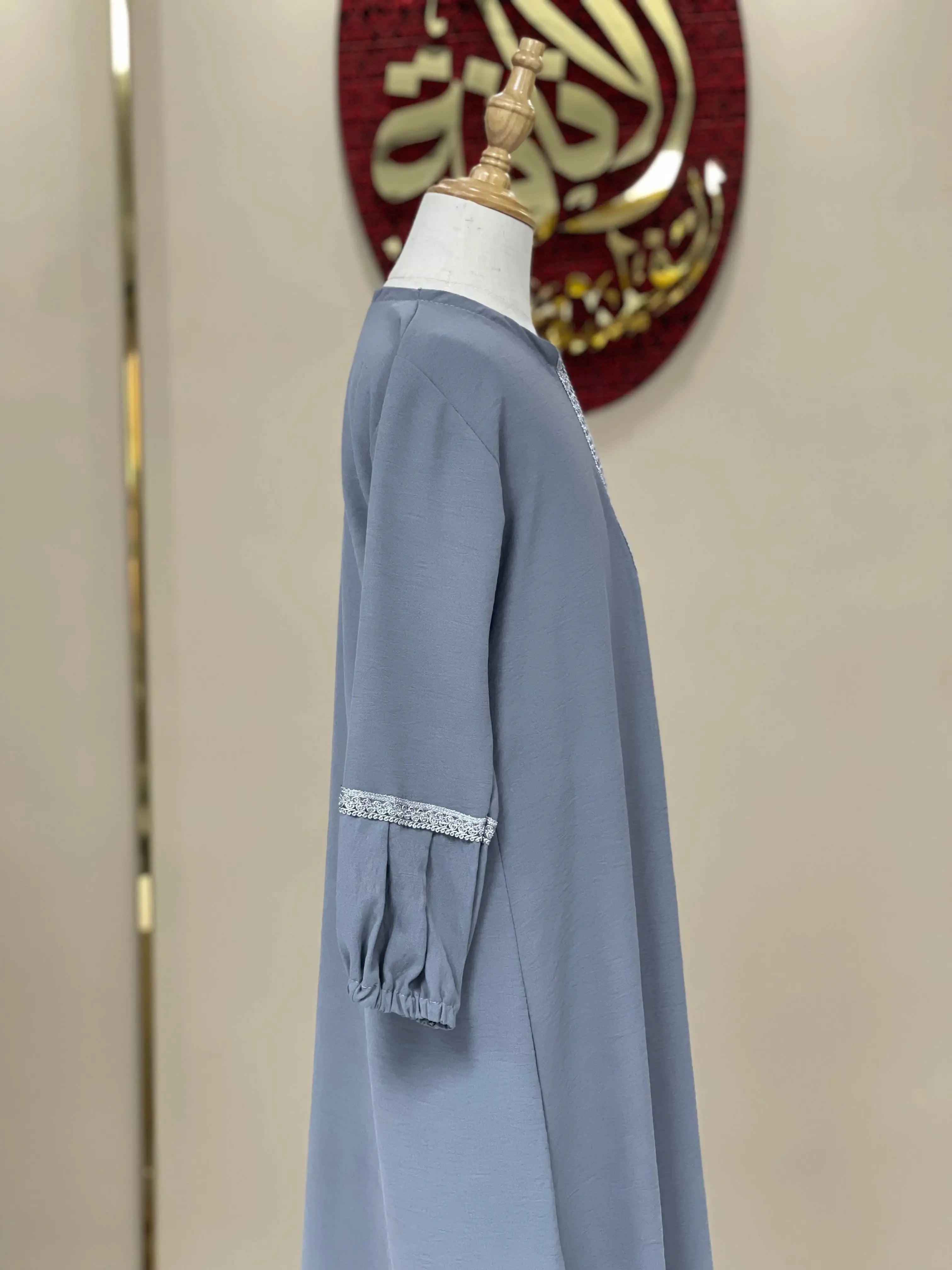 Side view of a girls embroidered abaya in gray with lace details on long sleeves by Palestinian Elegance
