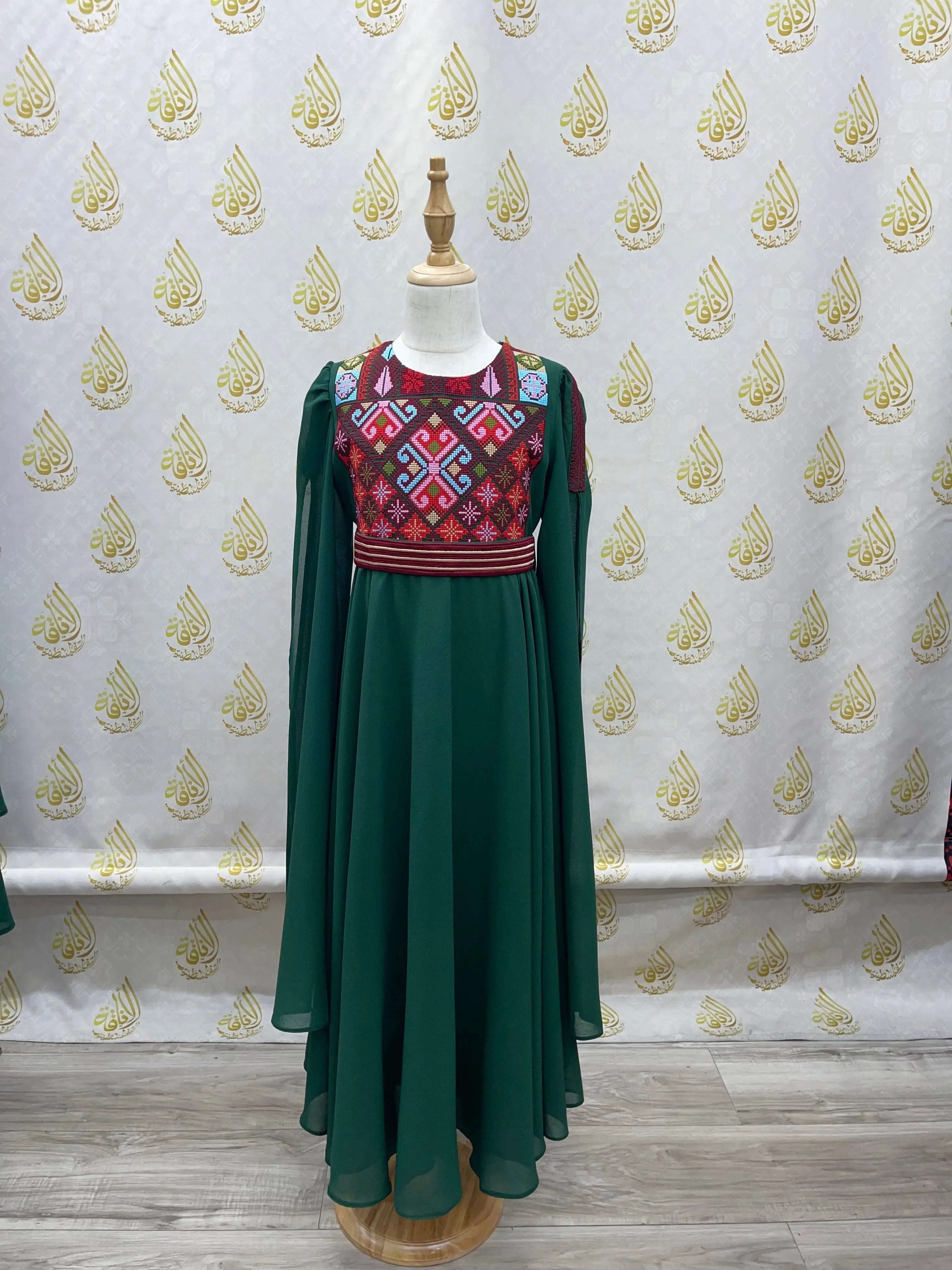 Palestinian girls embroidered dress with colorful geometric embroidery and flowing green fabric by Palestinian Elegance