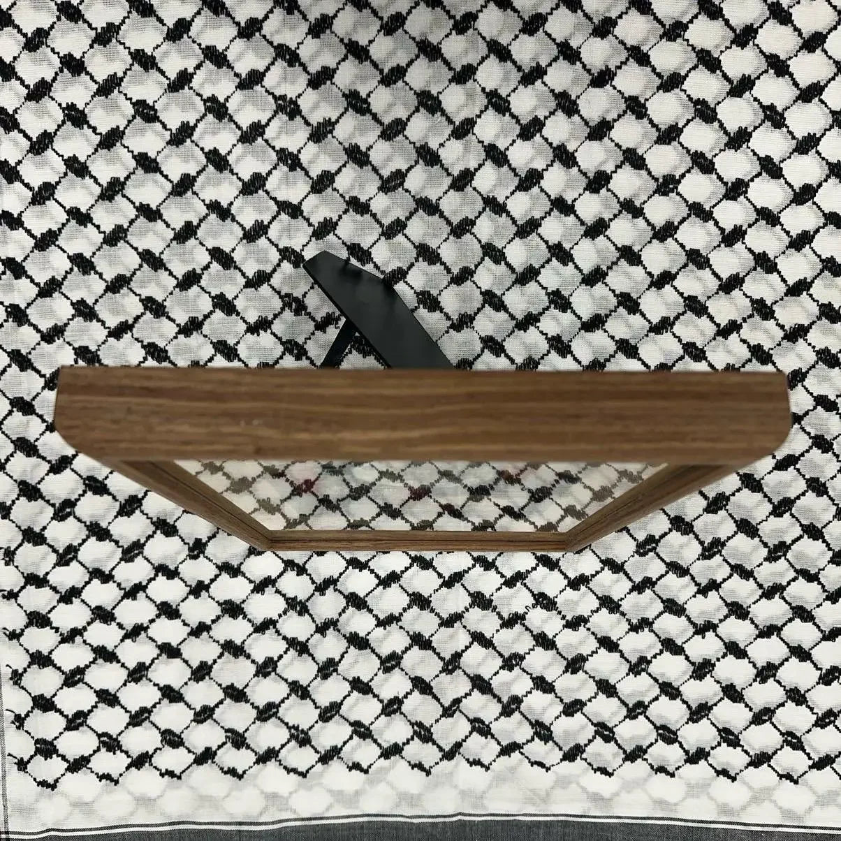 Wooden frame displayed on black and white Palestinian embroidered wall art textile with intricate patterns