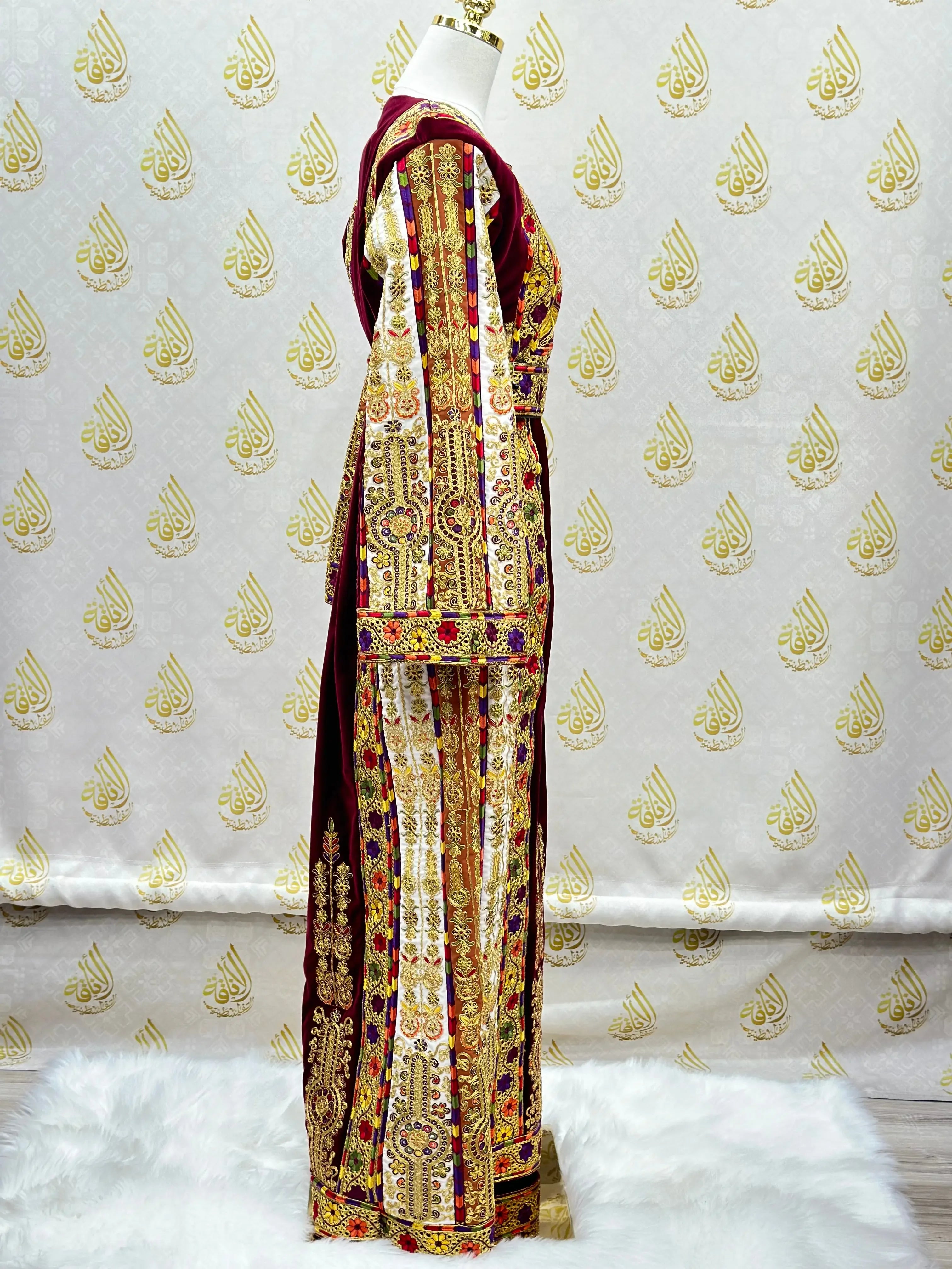 Velvet Palestinian dress with intricate gold and red embroidery by Palestinian Elegance displayed on a mannequin