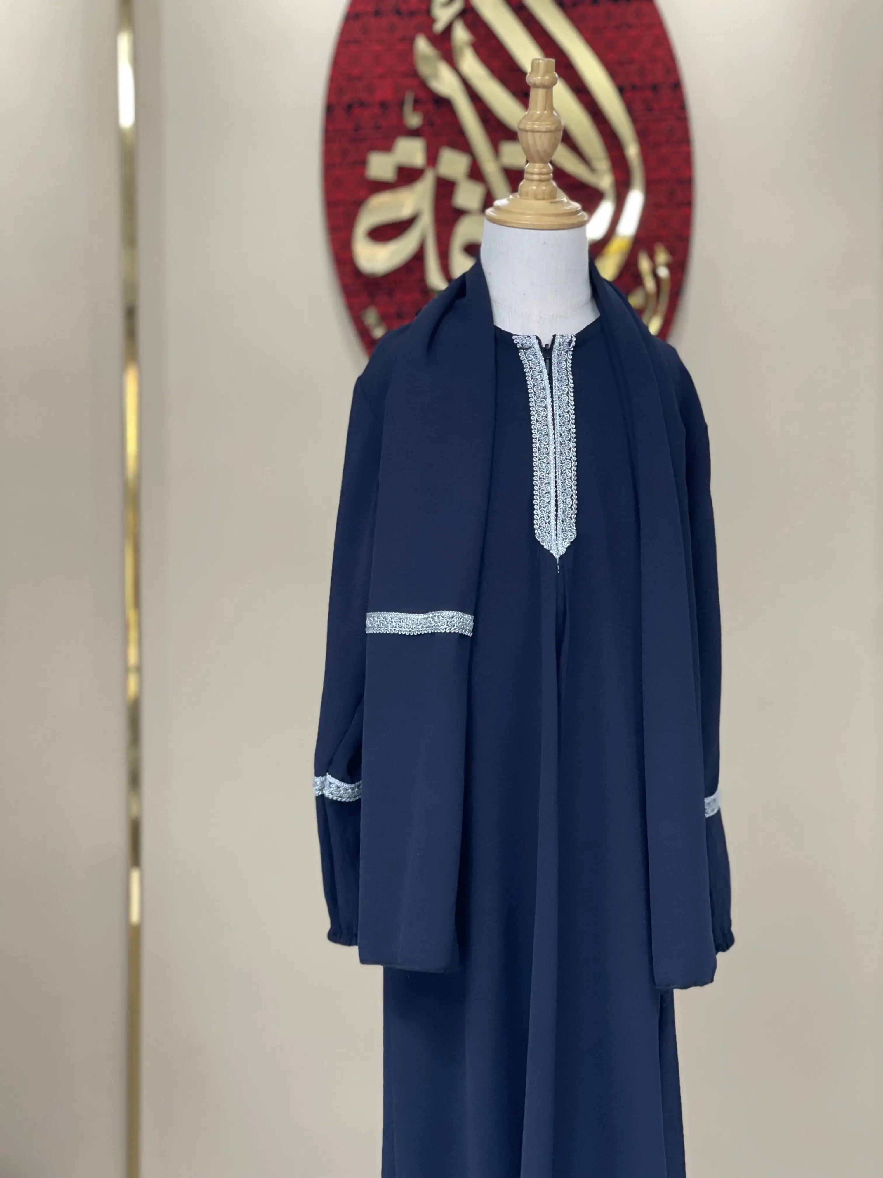 Navy blue girls embroidered abaya with silver detailing displayed on a mannequin by Palestinian Elegance