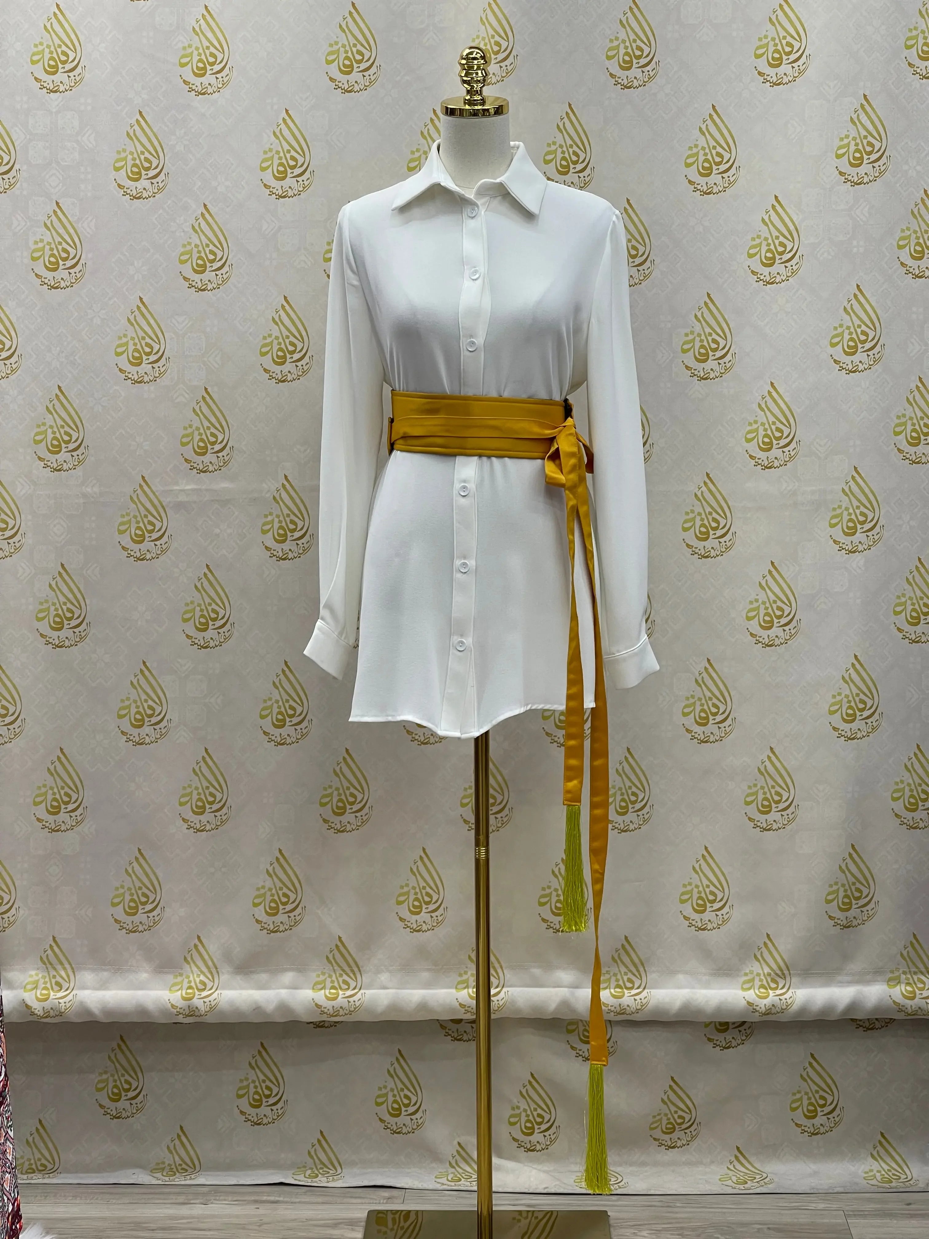 Luxury satin belt for dresses in gold wrapped around white button-down shirt dress on mannequin