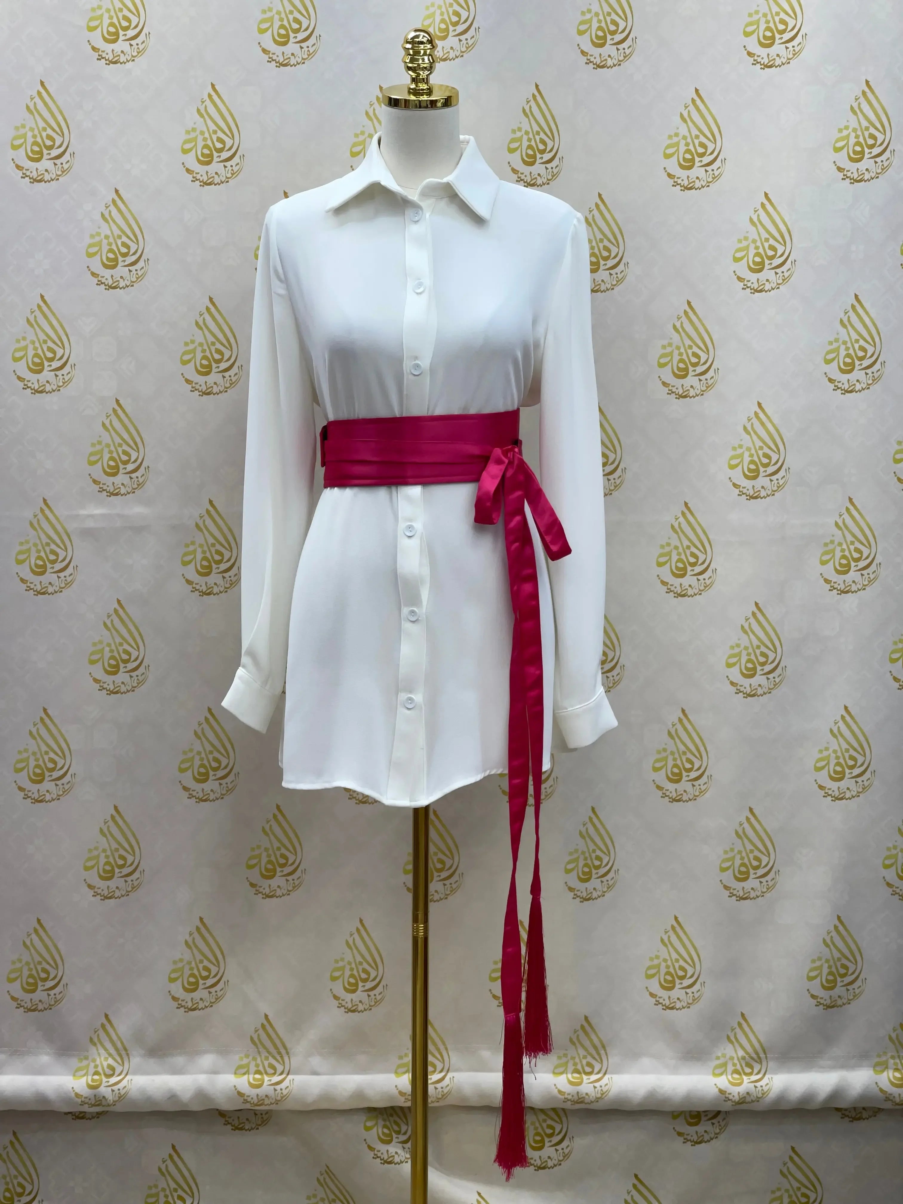 Luxury satin belt for dresses in deep pink wrapped around white button-down shirt dress on mannequin