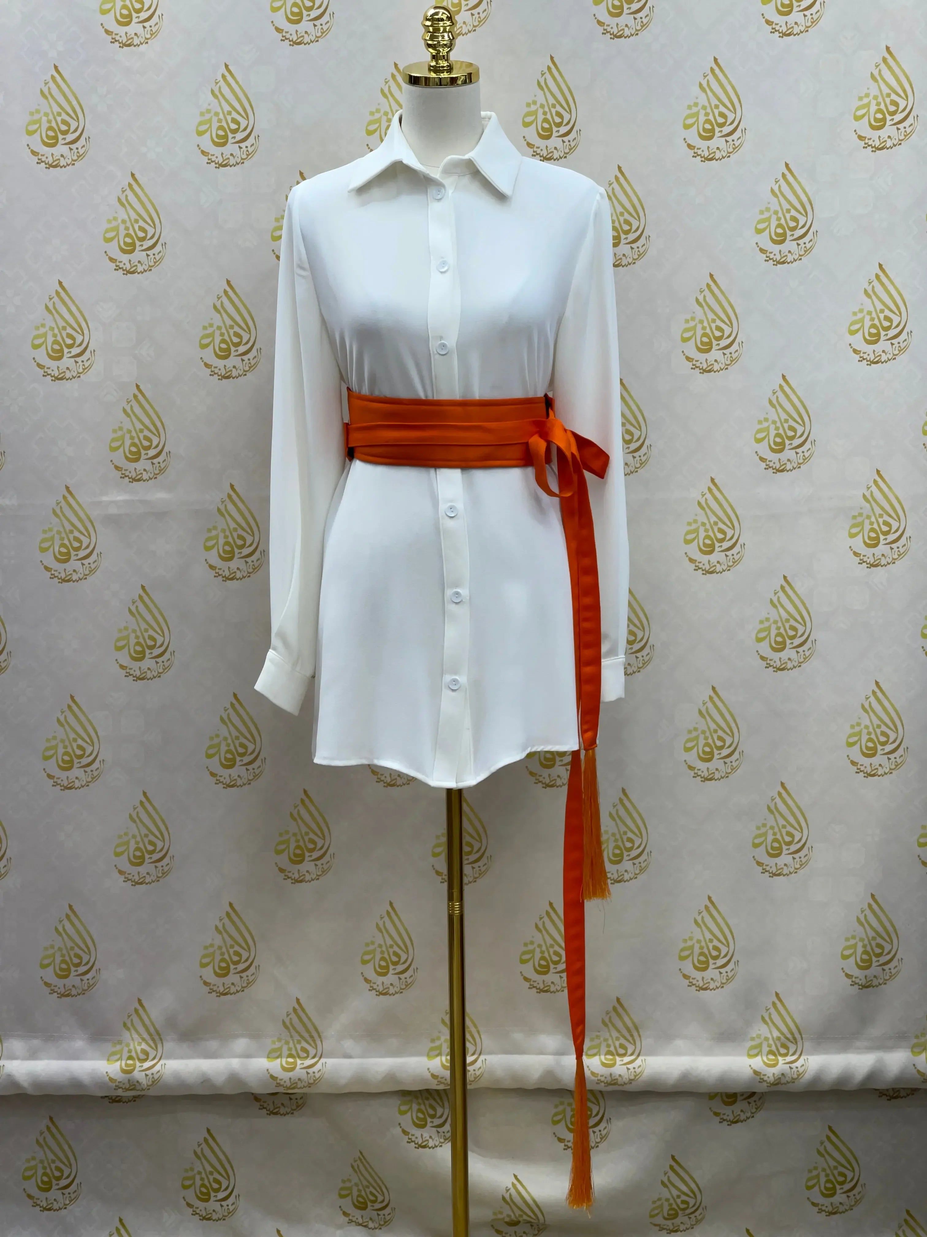 Luxury satin belt for dresses in rich orange wrapped around white button-down shirt on mannequin