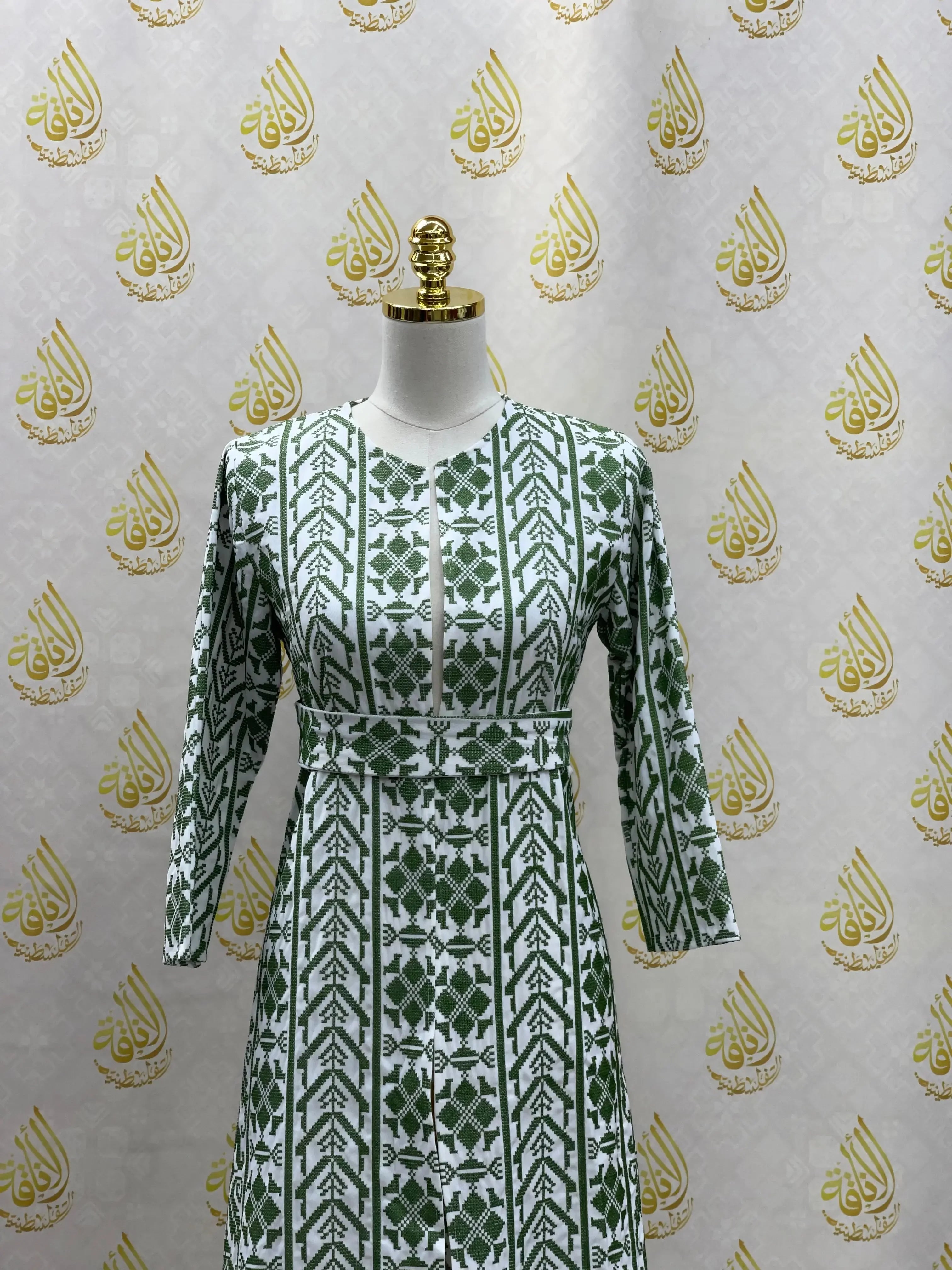 Embroidered cardigan for kids in white and green geometric pattern by Palestinian Elegance on mannequin
