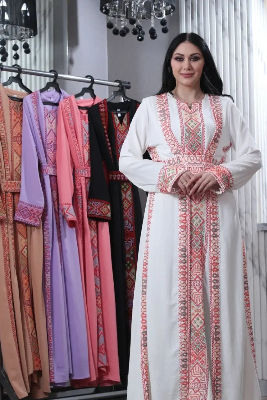 Palestinian Elegance embroidered abaya for women in white with traditional patterns worn by model beside colorful abayas on rack