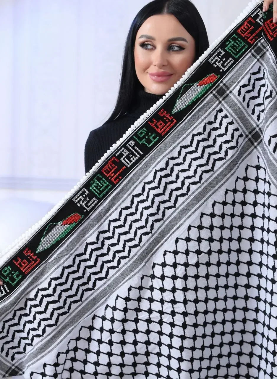 Woman holding embroidered Palestinian kuffiyeh with traditional black and white pattern and colorful border