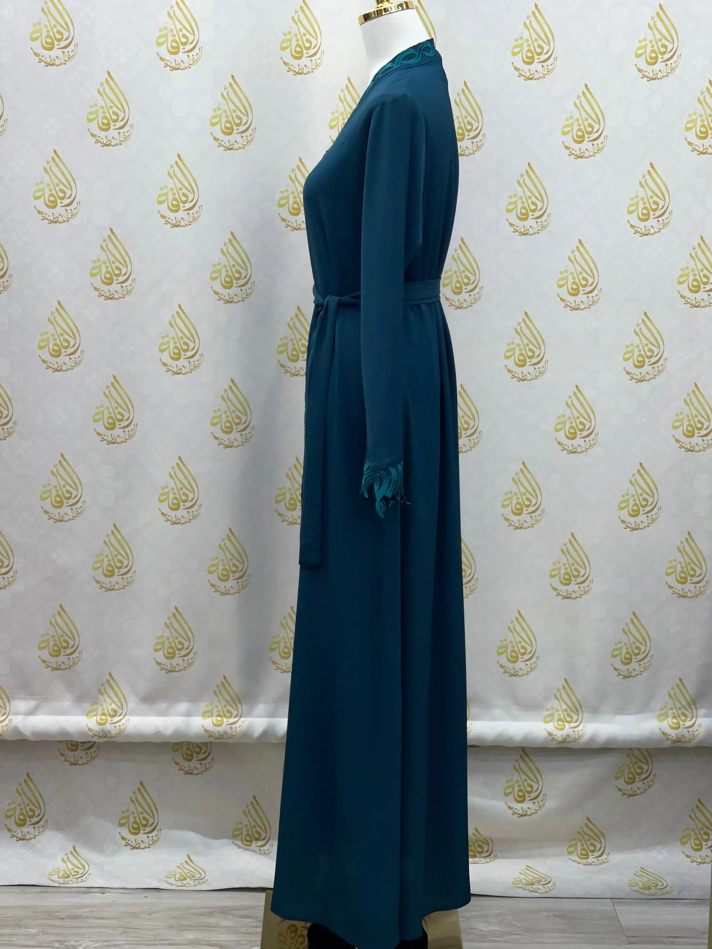 Elegant embroidered abaya in dark teal displayed on mannequin side view by Palestinian Elegance