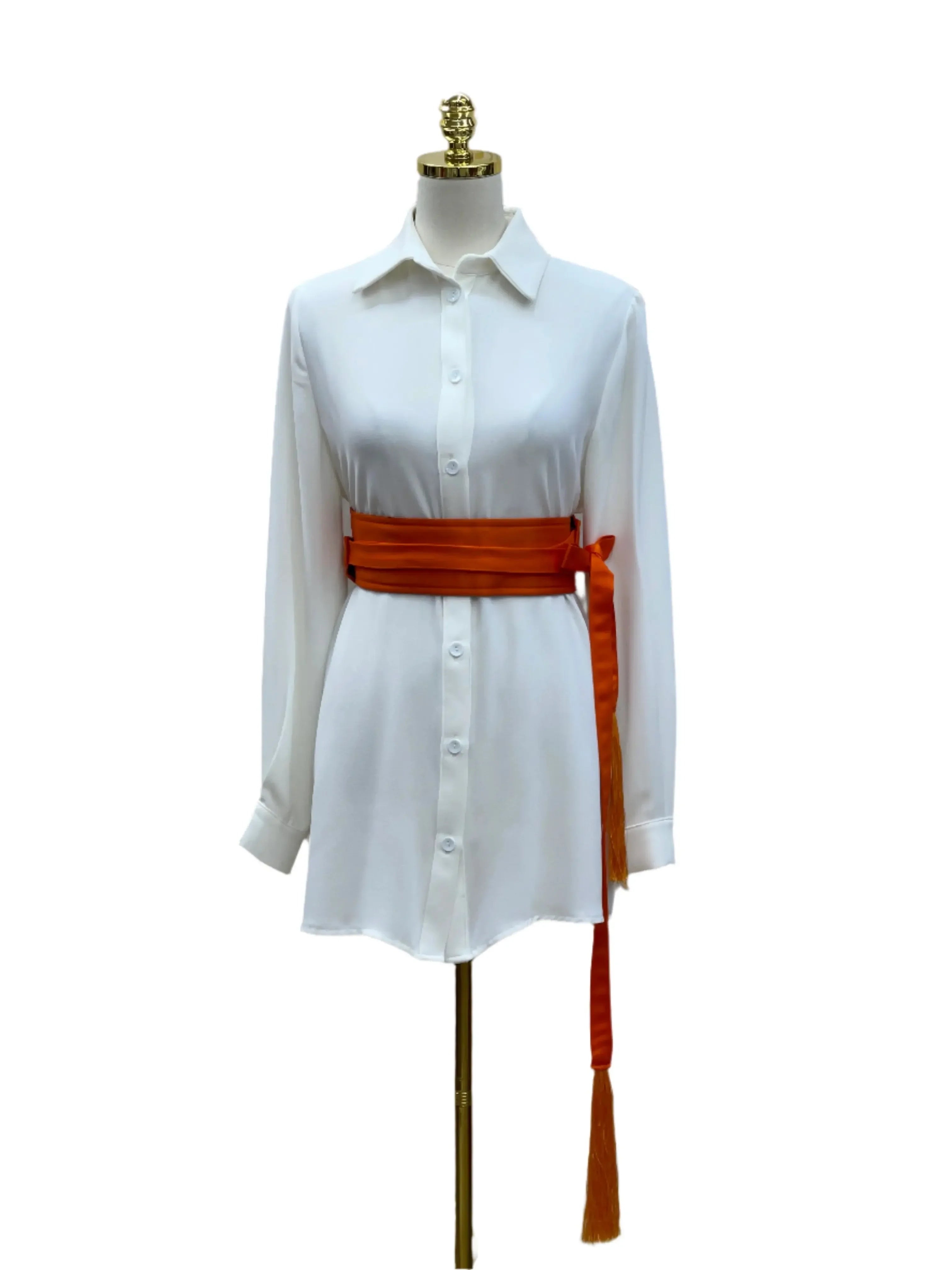 Luxury satin belt for dresses in orange styled on a white button-down dress on a mannequin