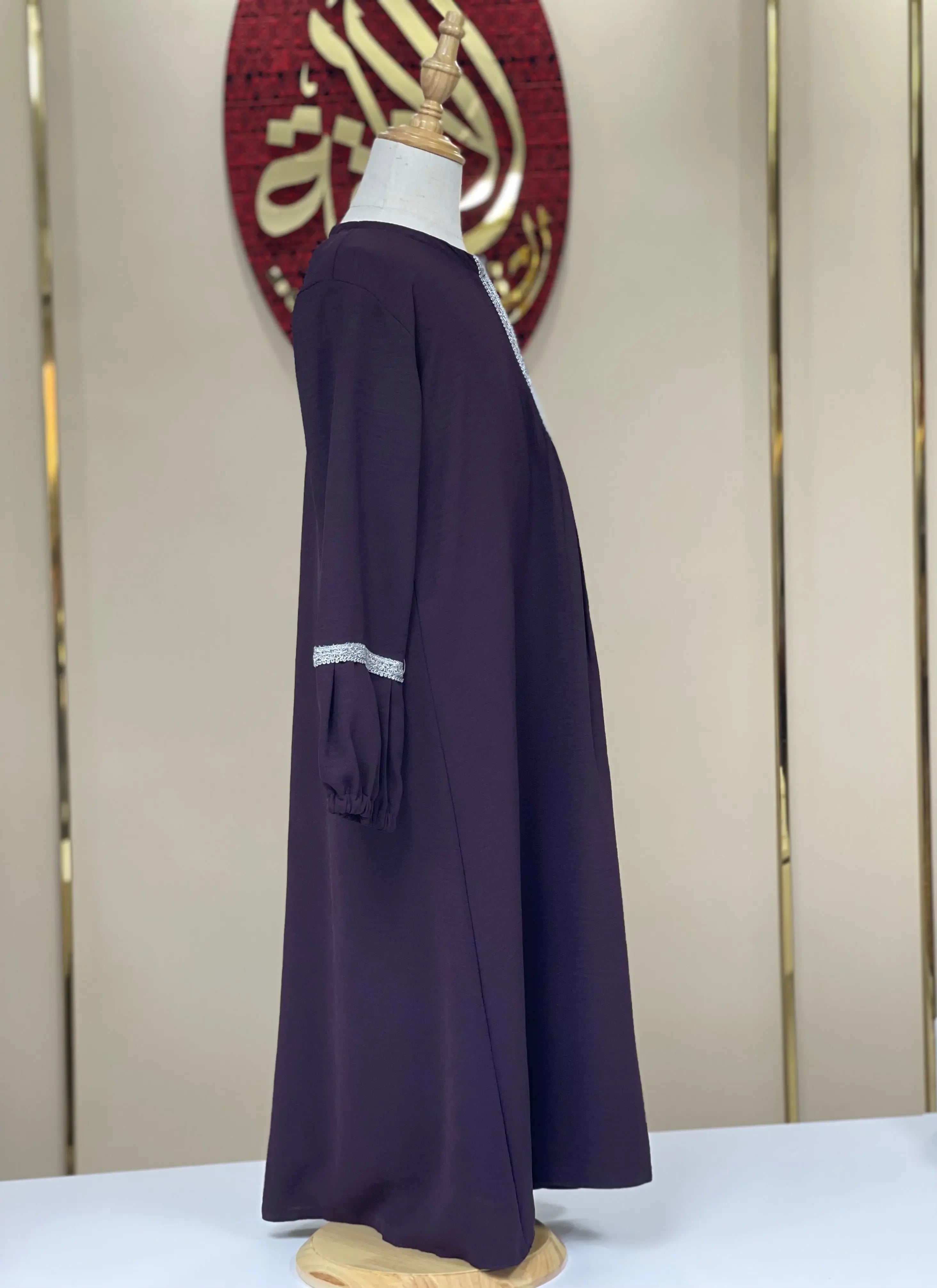 Palestinian Elegance girls embroidered abaya in dark purple with subtle white embroidery on sleeves displayed on a mannequin