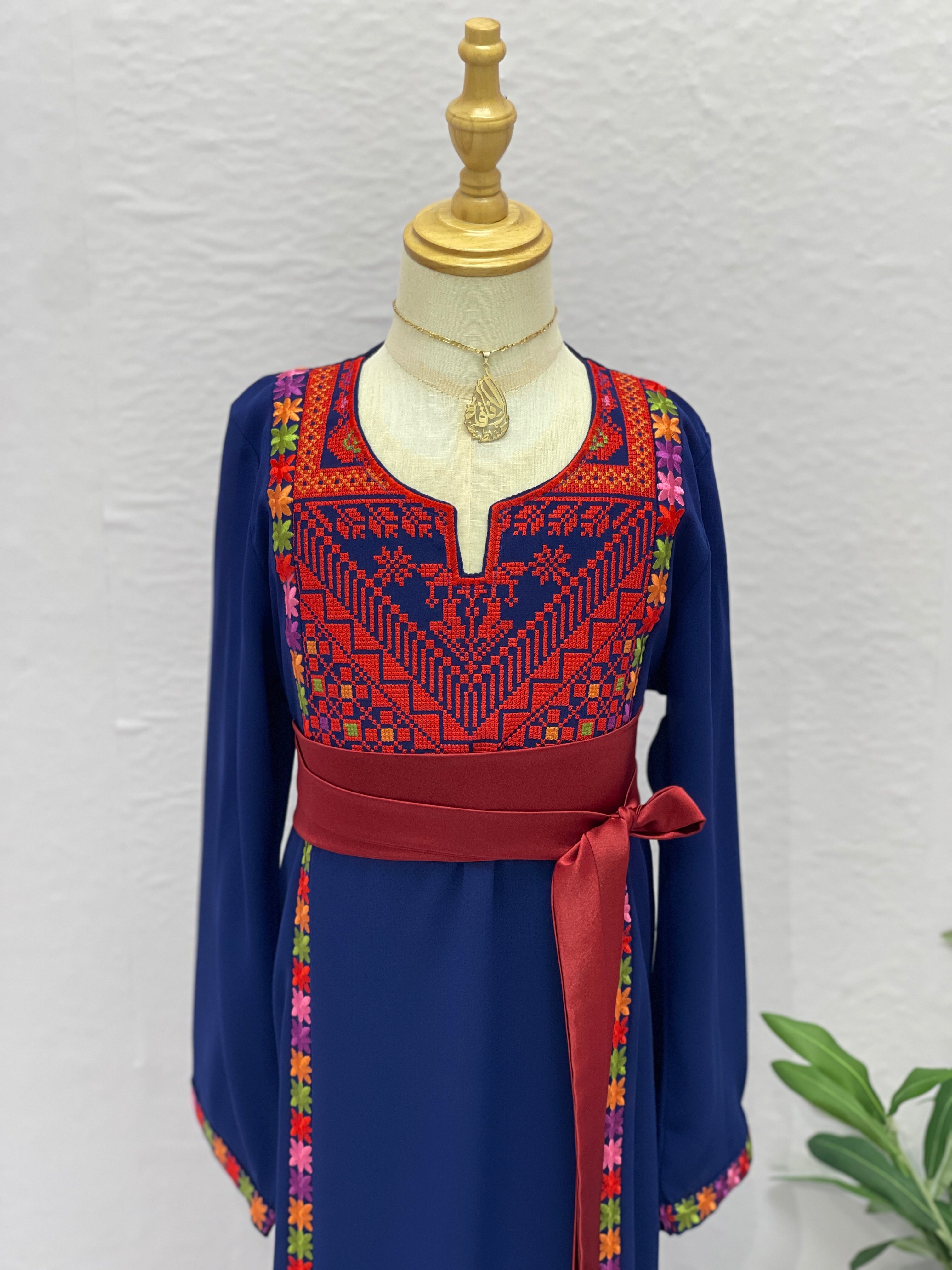 Traditional embroidered dress on a mannequin against a light gray background