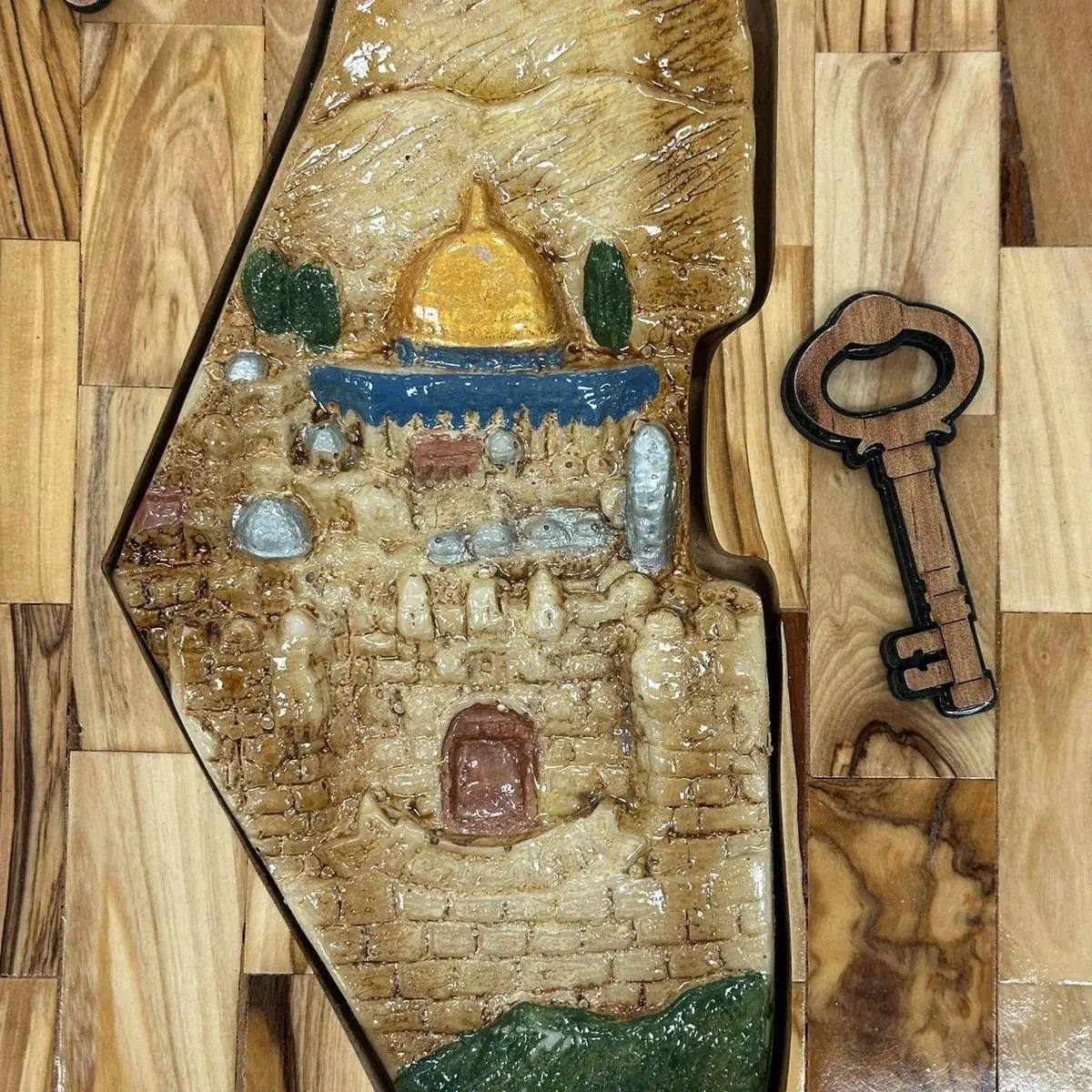 Handmade Palestinian wall art featuring glazed ceramic depiction of a golden dome and ancient stone building
