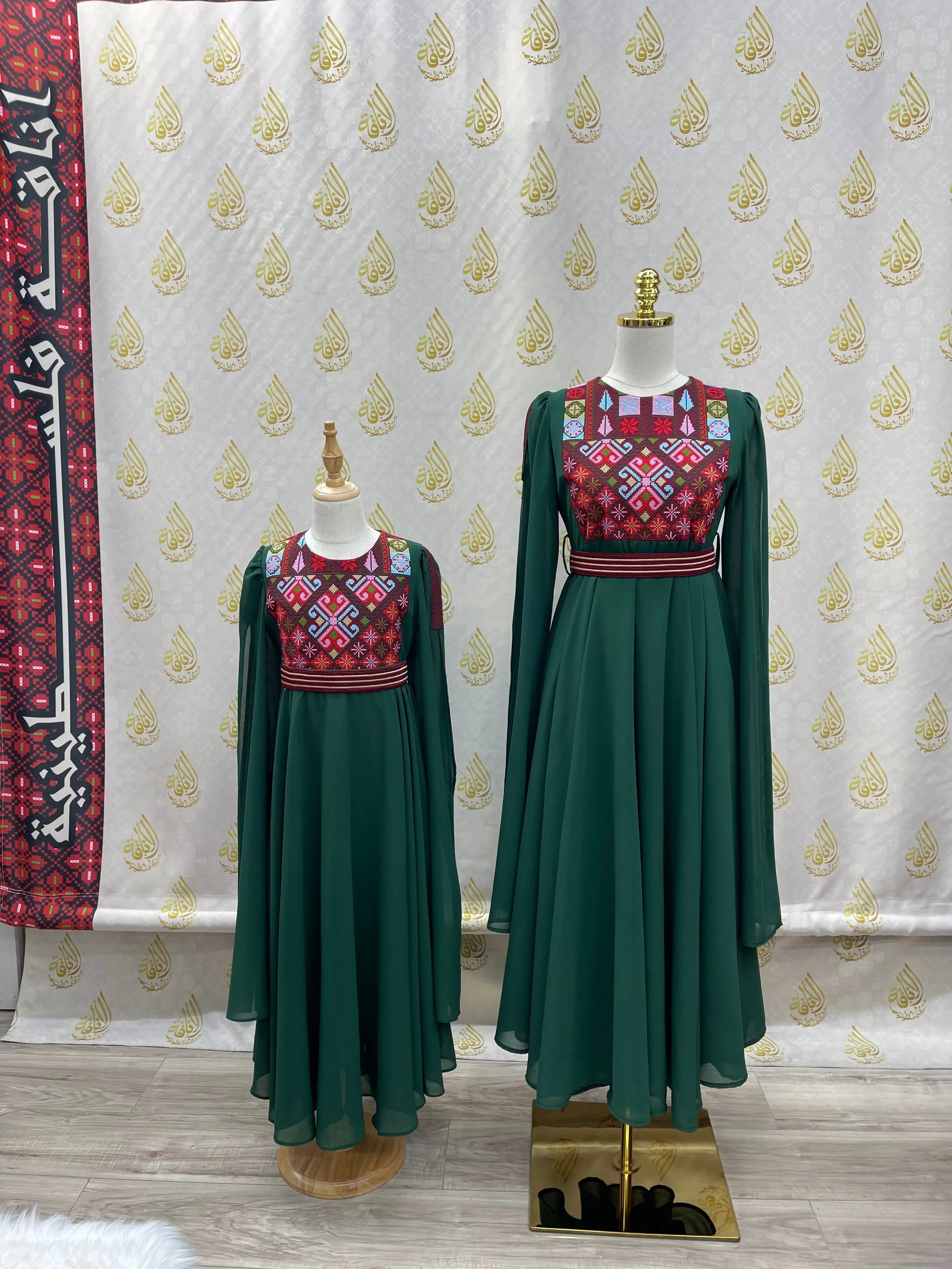 Palestinian girls embroidered dress in green with traditional red and multicolor embroidery on mannequins