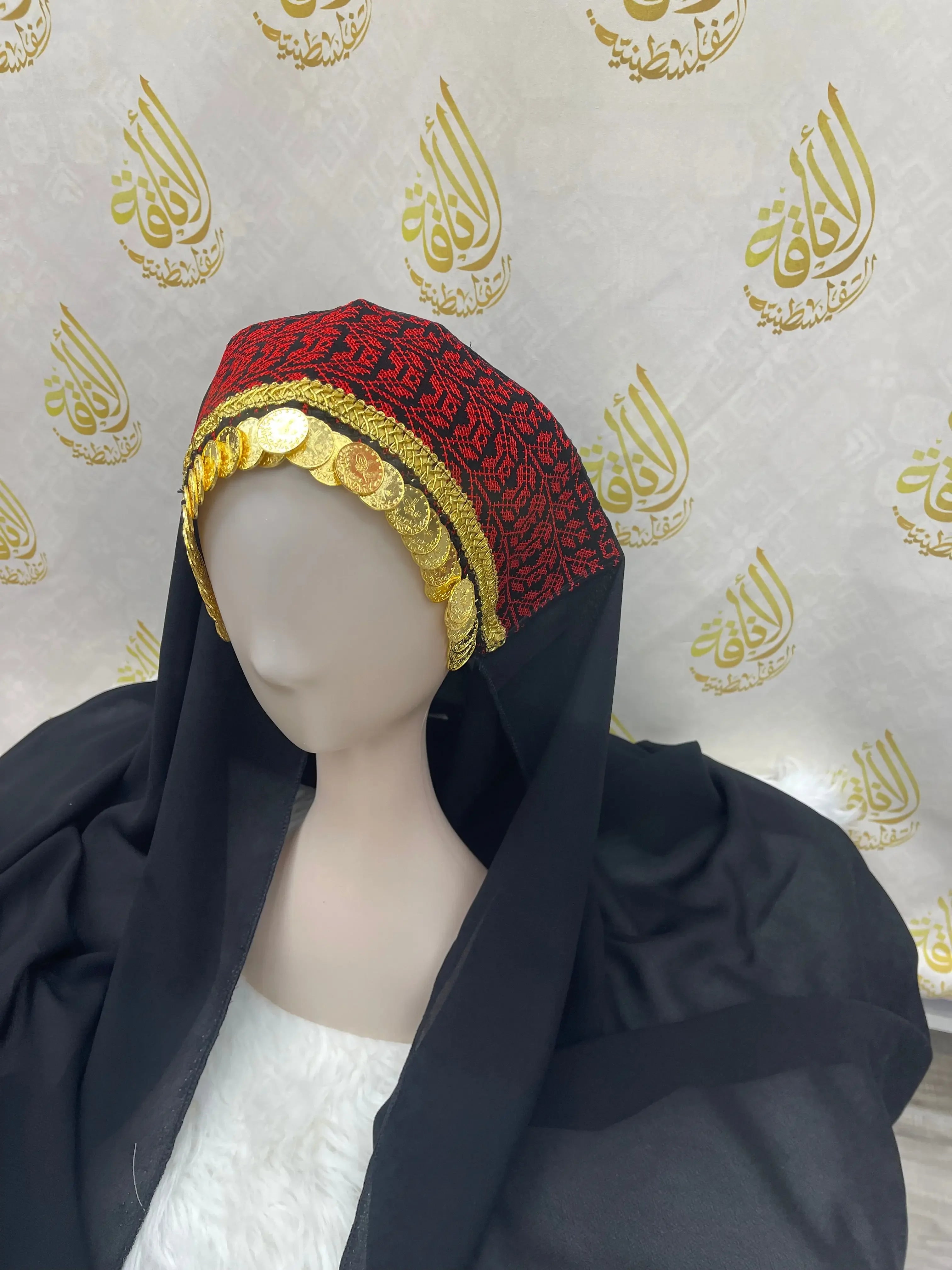 Palestinian embroidered khirka shawl with red and black embroidery and gold coin decorations displayed on a mannequin