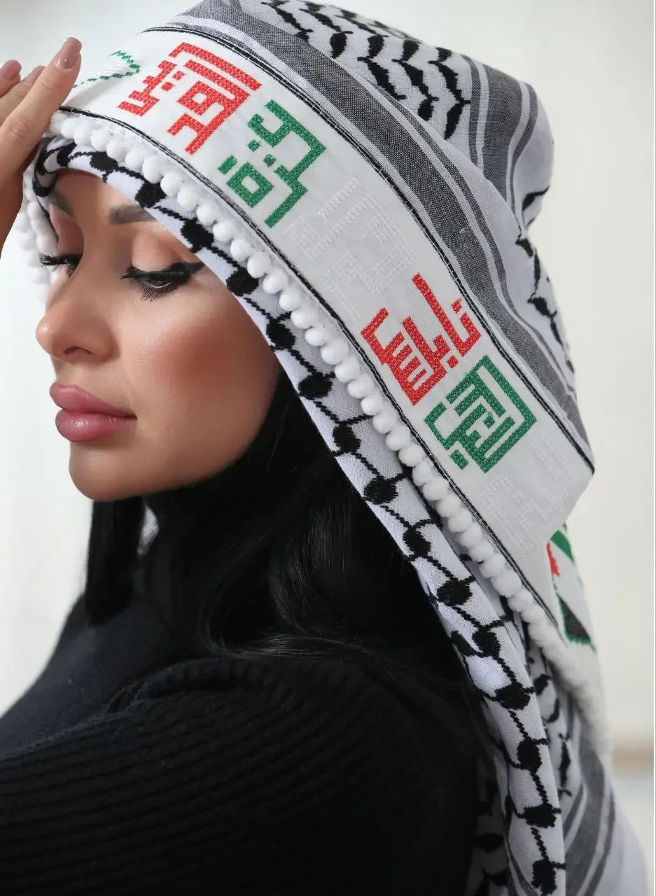Embroidered Palestinian kuffiyeh worn by woman featuring traditional black and white pattern with red and green embroidery
