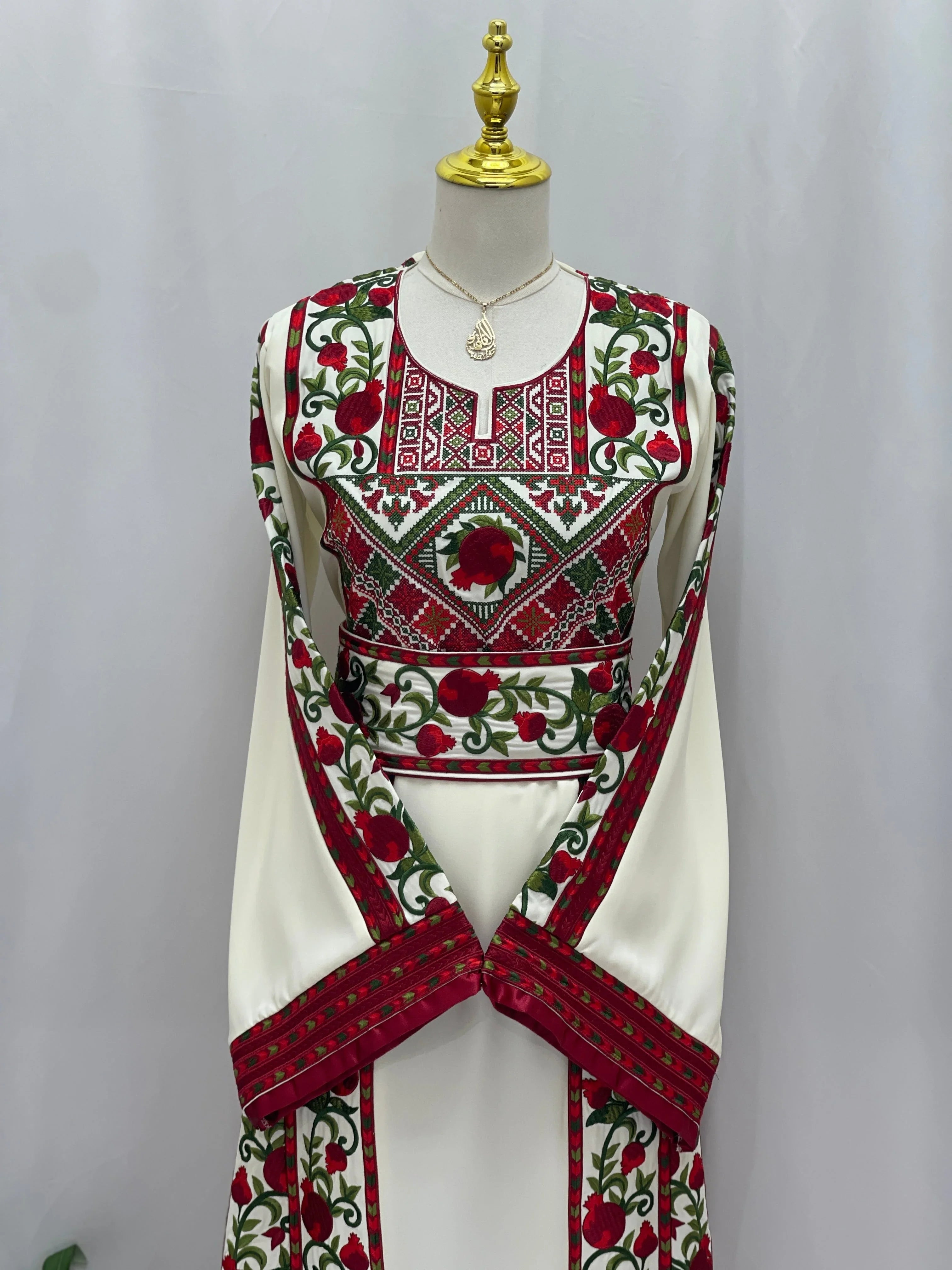 Al Romana Pomegranate Embroidered Thoub by Palestinian Elegance featuring intricate red and green embroidery on white fabric