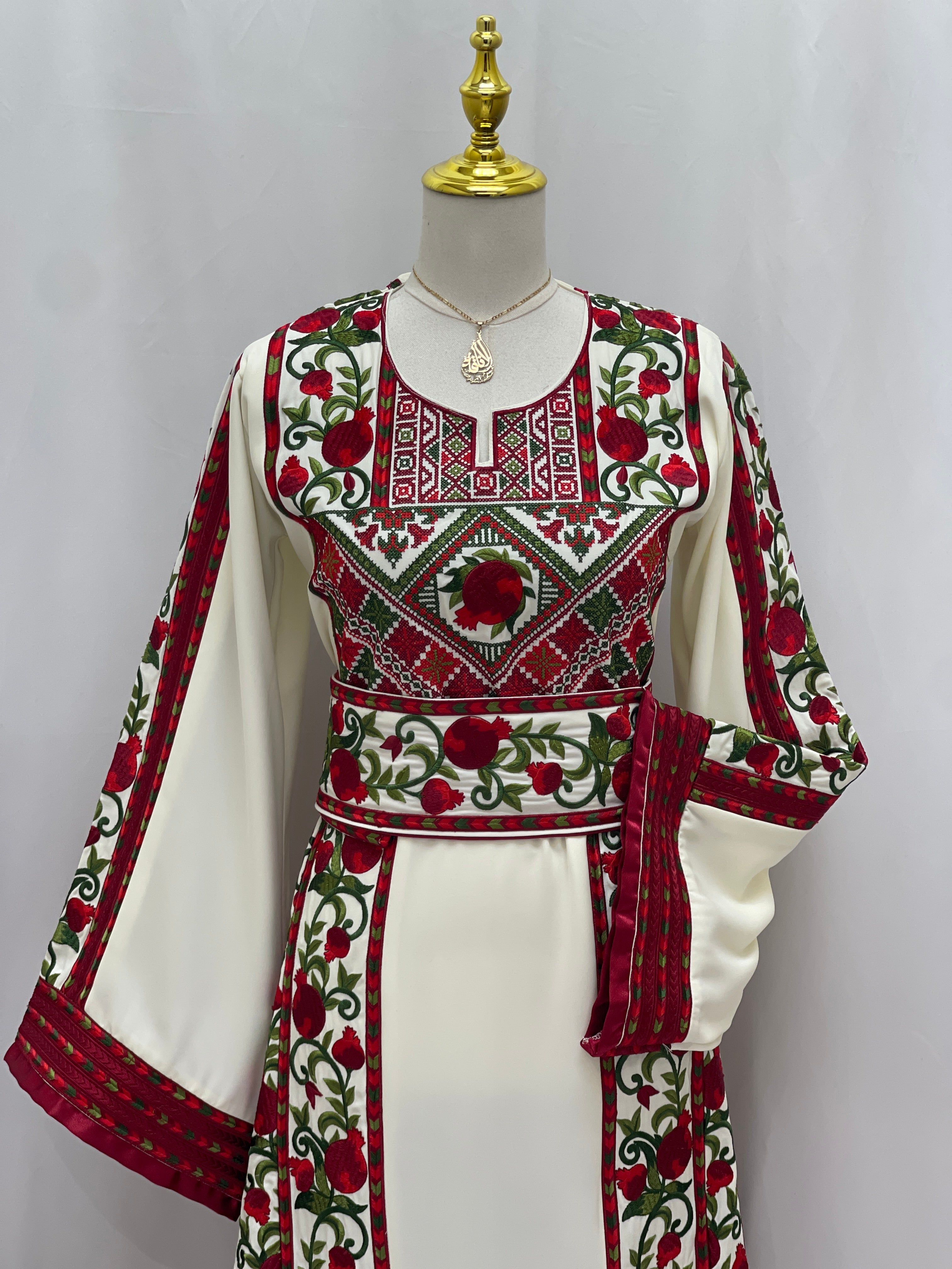Al Romana Pomegranate Embroidered Thoub by Palestinian Elegance with intricate red and green pomegranate embroidery on white fabric