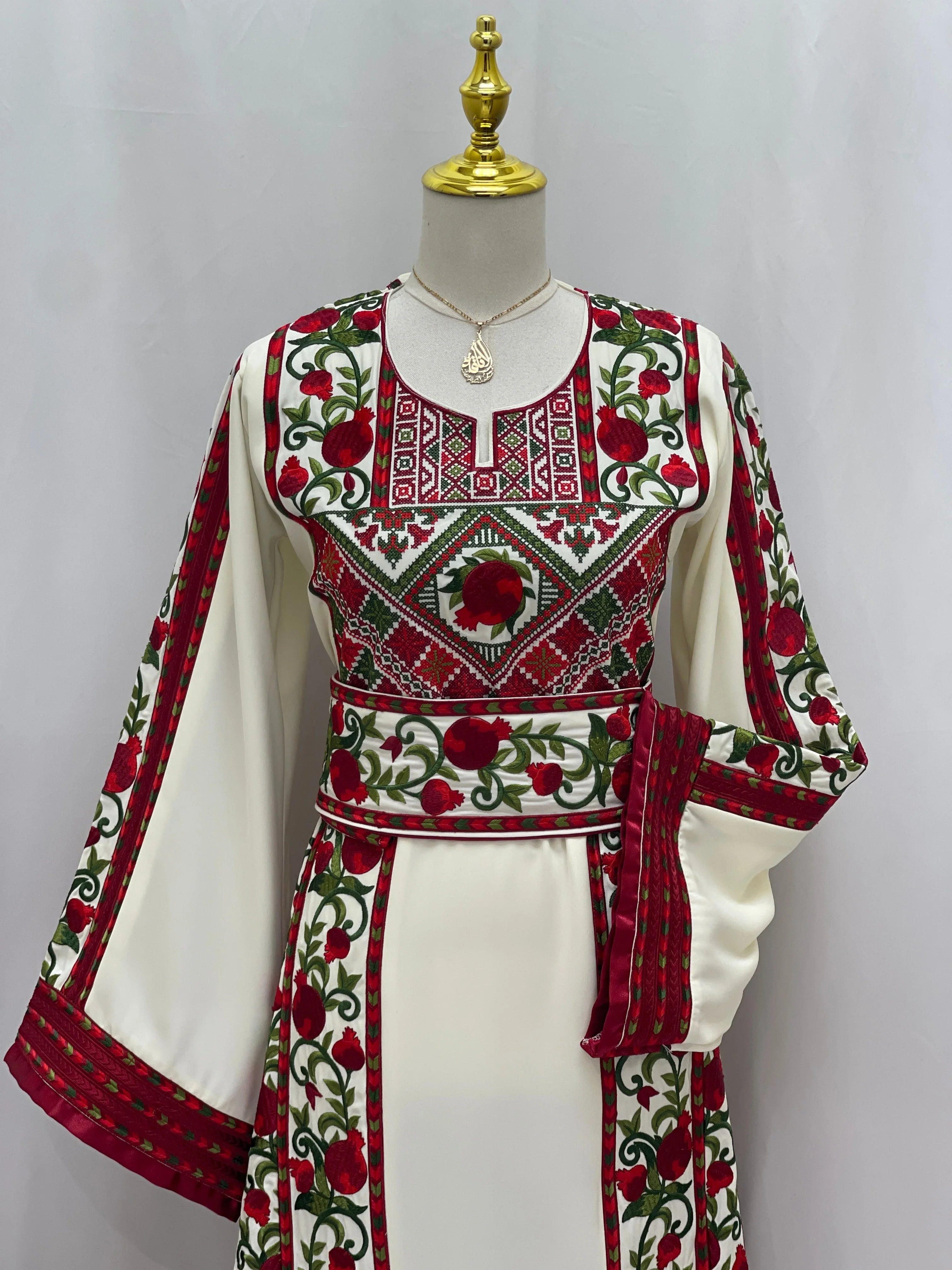 Al Romana Pomegranate Embroidered Thoub by Palestinian Elegance with intricate red and green pomegranate embroidery on white fabric