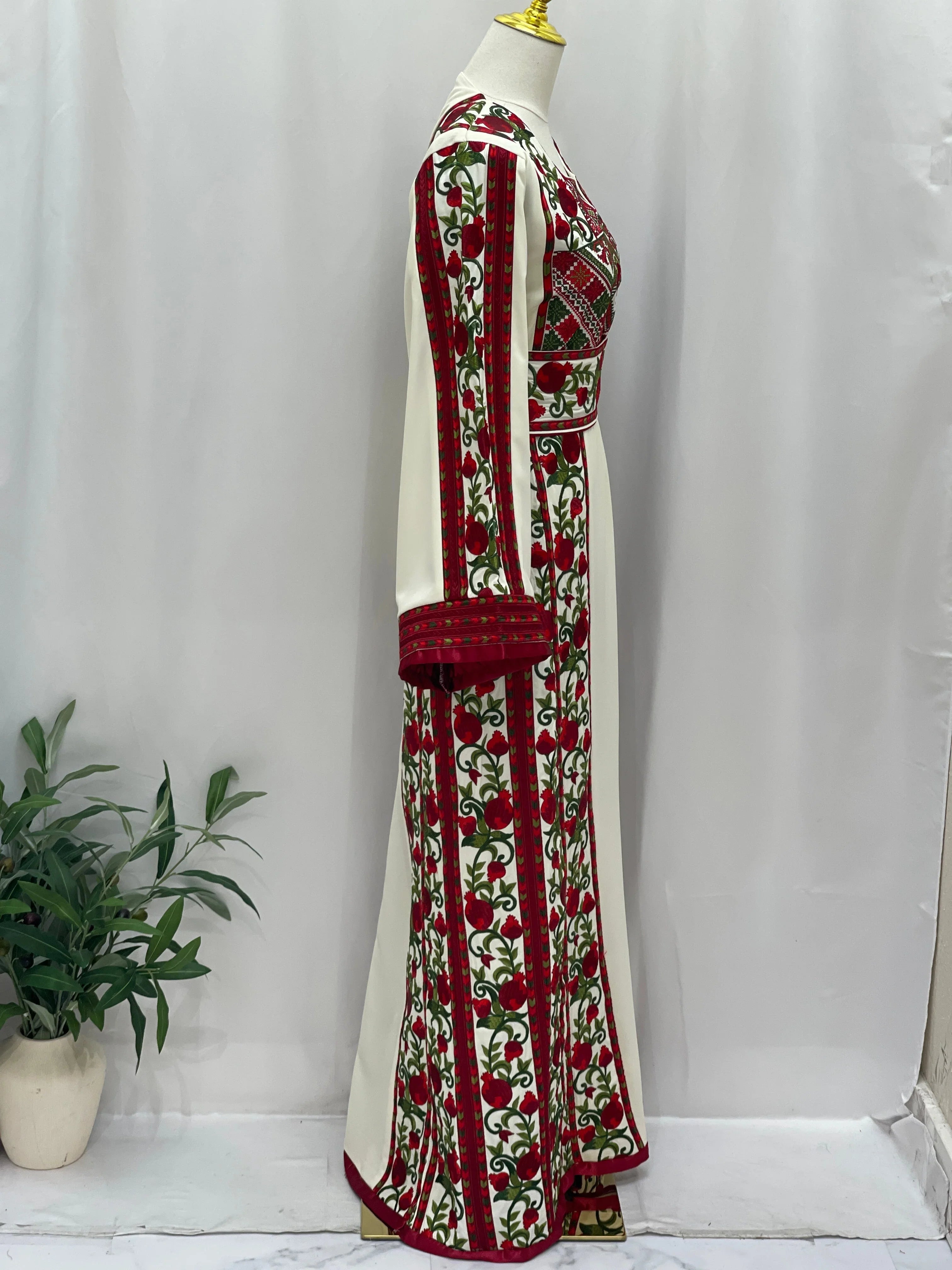 Side view of Al Romana Pomegranate Embroidered Thoub with intricate red and green embroidery on white fabric