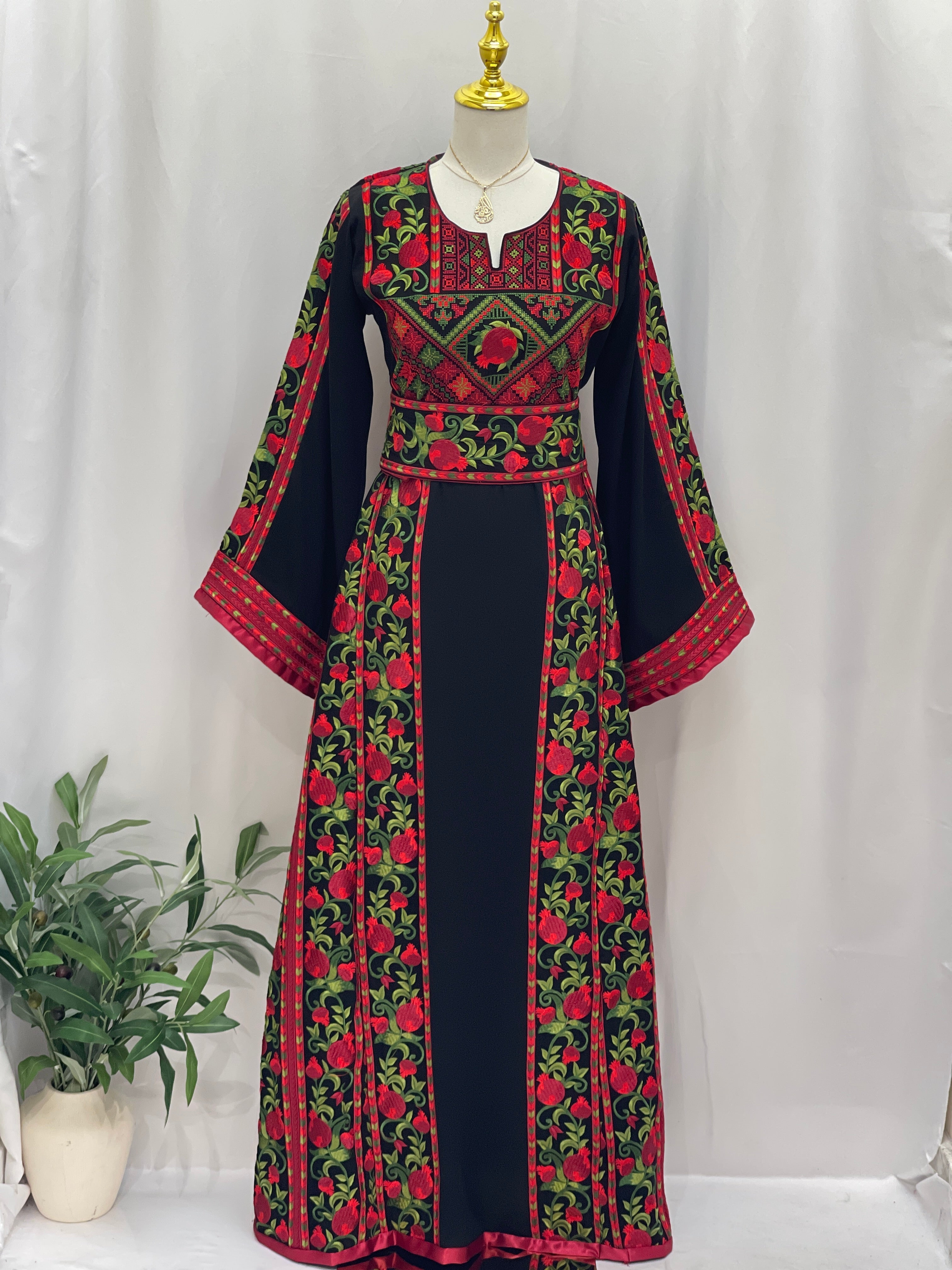 Al Romana Pomegranate Embroidered Thoub by Palestinian Elegance with red and green floral embroidery on black fabric