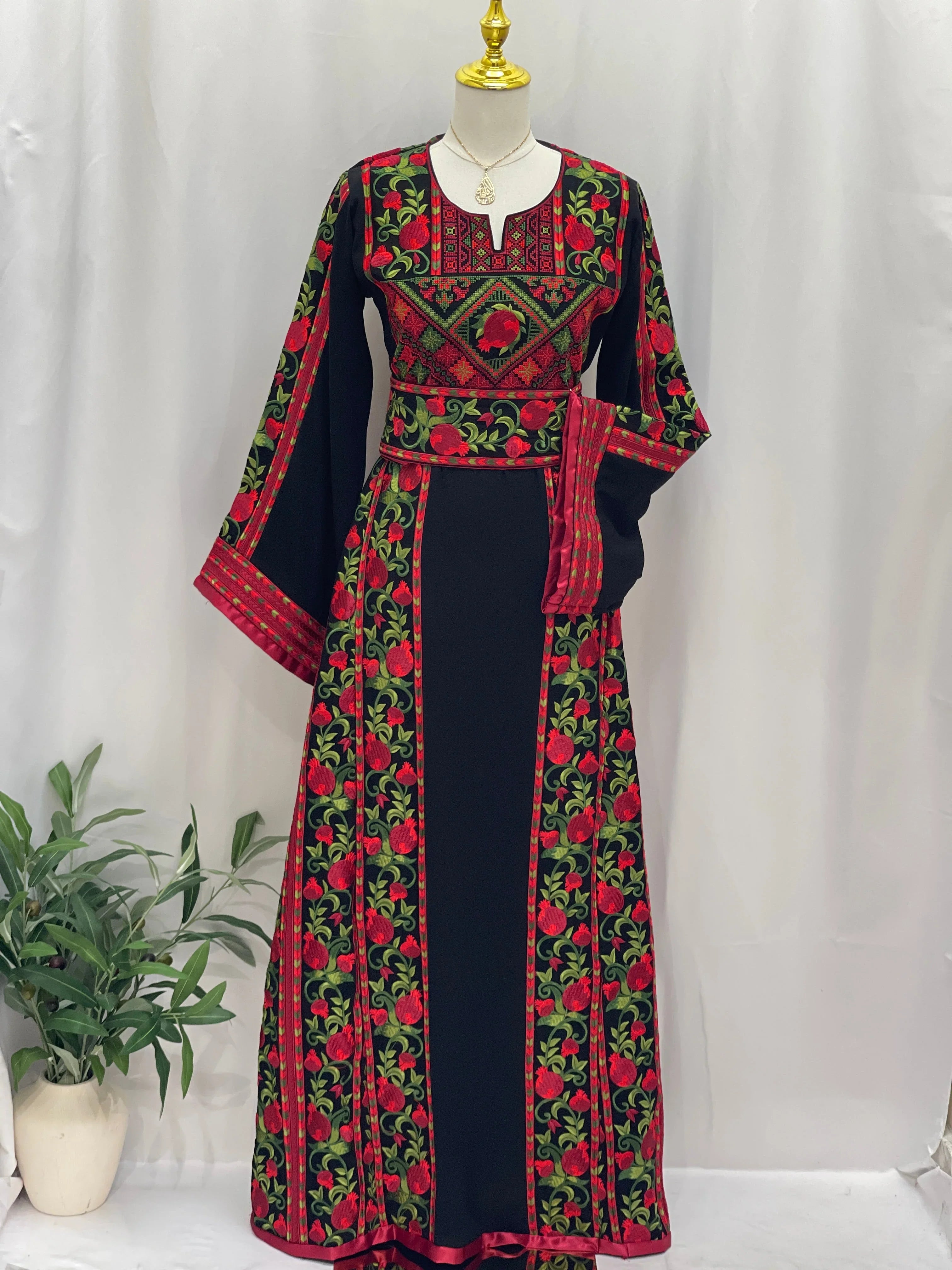 Al Romana Pomegranate Embroidered Thoub by Palestinian Elegance with intricate red and green floral patterns on black fabric