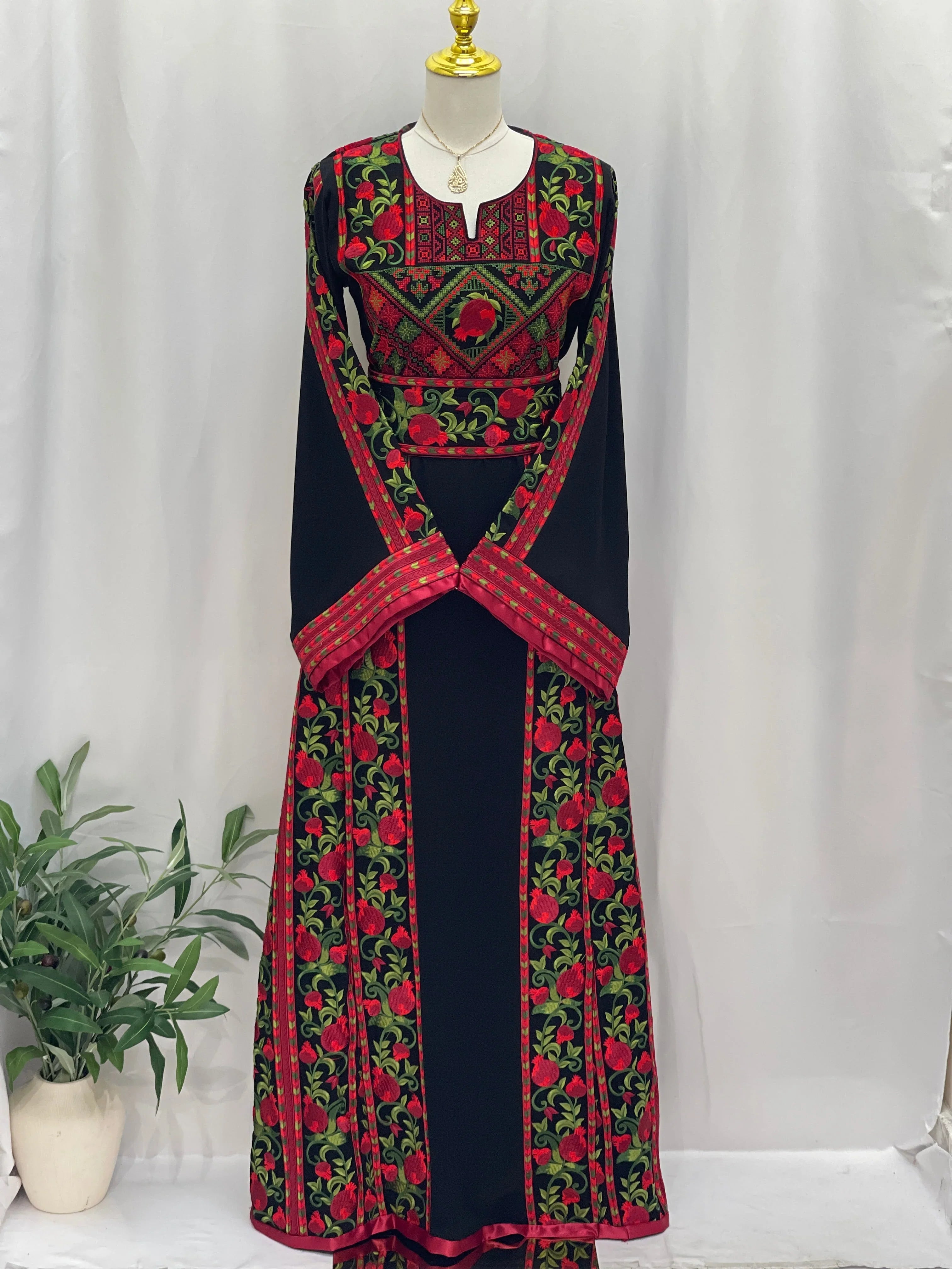 Al Romana Pomegranate Embroidered Thoub by Palestinian Elegance with intricate red and green floral embroidery on black fabric