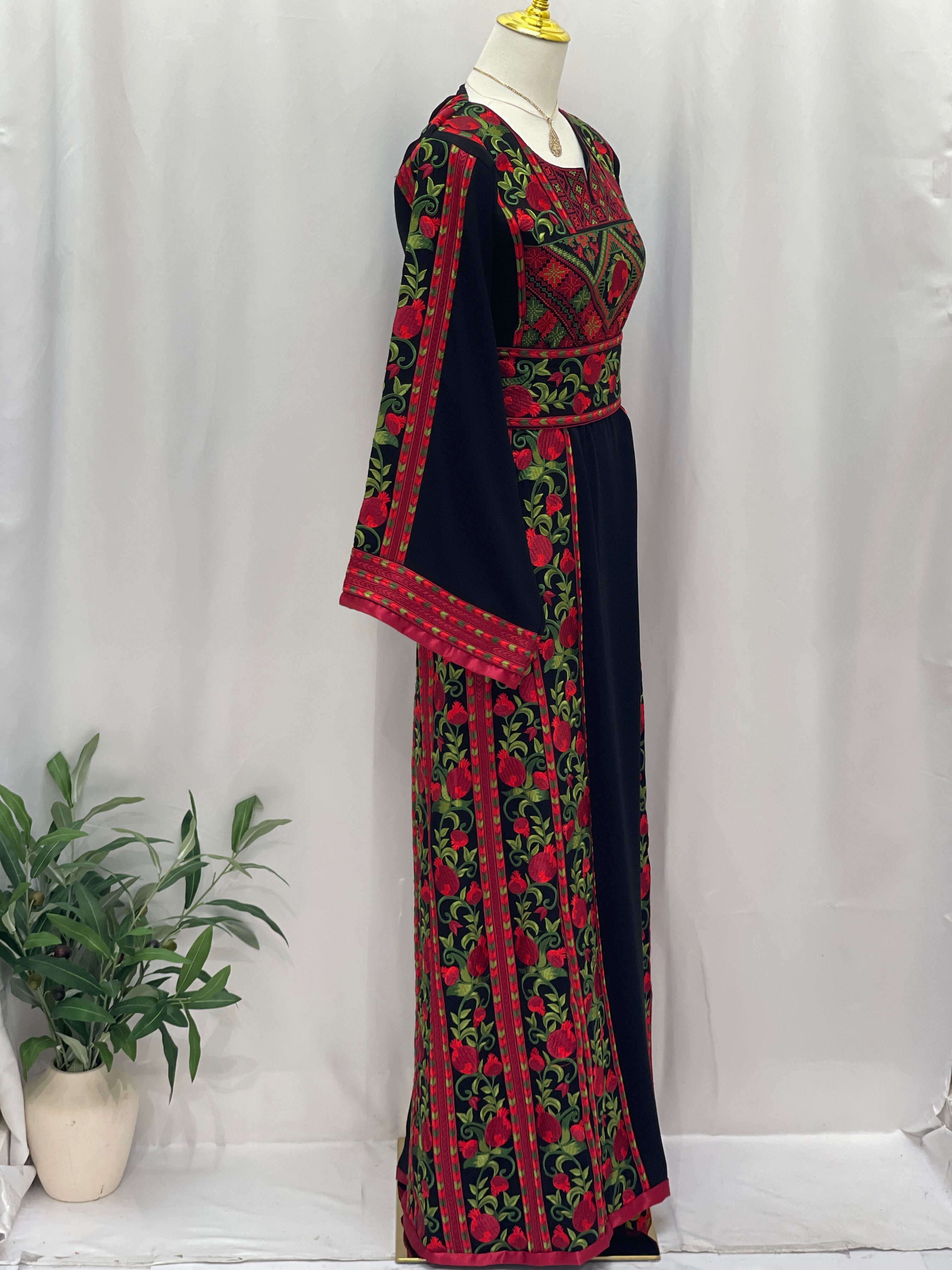 Palestinian Elegance Al Romana Pomegranate Embroidered Thoub featuring intricate red and green embroidery on black fabric