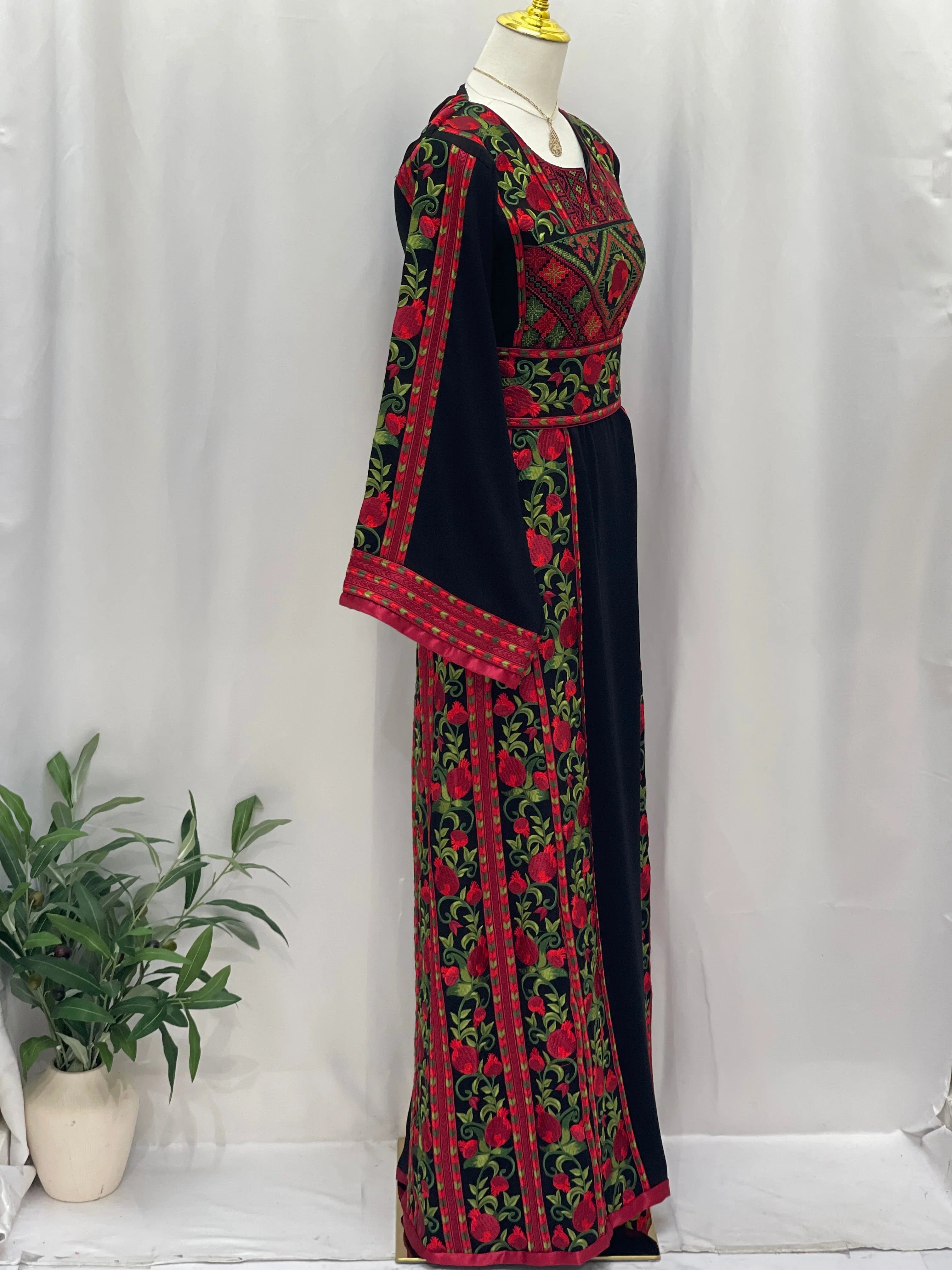 Palestinian Elegance Al Romana Pomegranate Embroidered Thoub featuring intricate red and green embroidery on black fabric