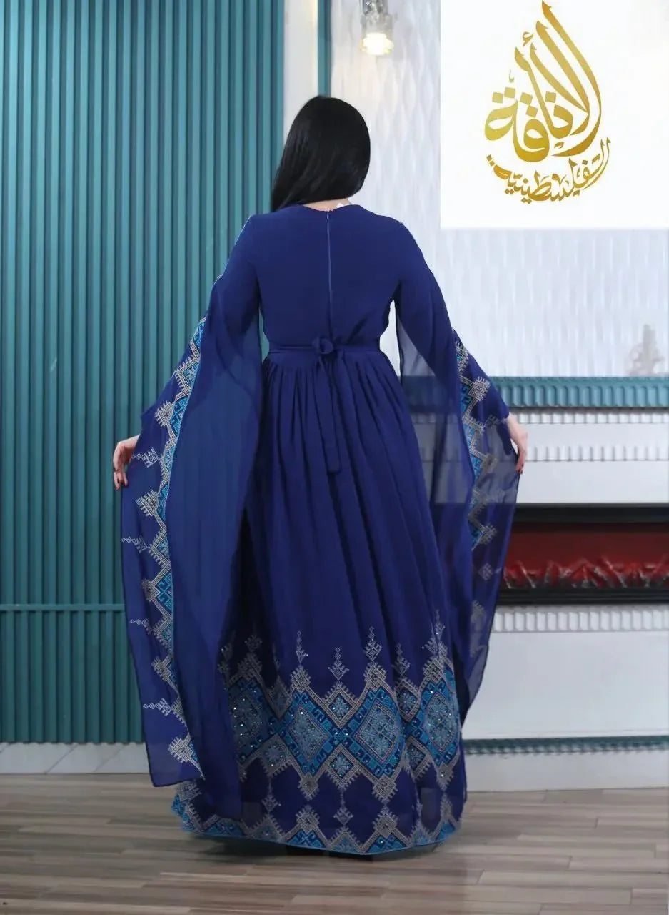Back view of a woman wearing a modern embroidered Palestinian dress in navy blue with intricate sleeve and hem embroidery