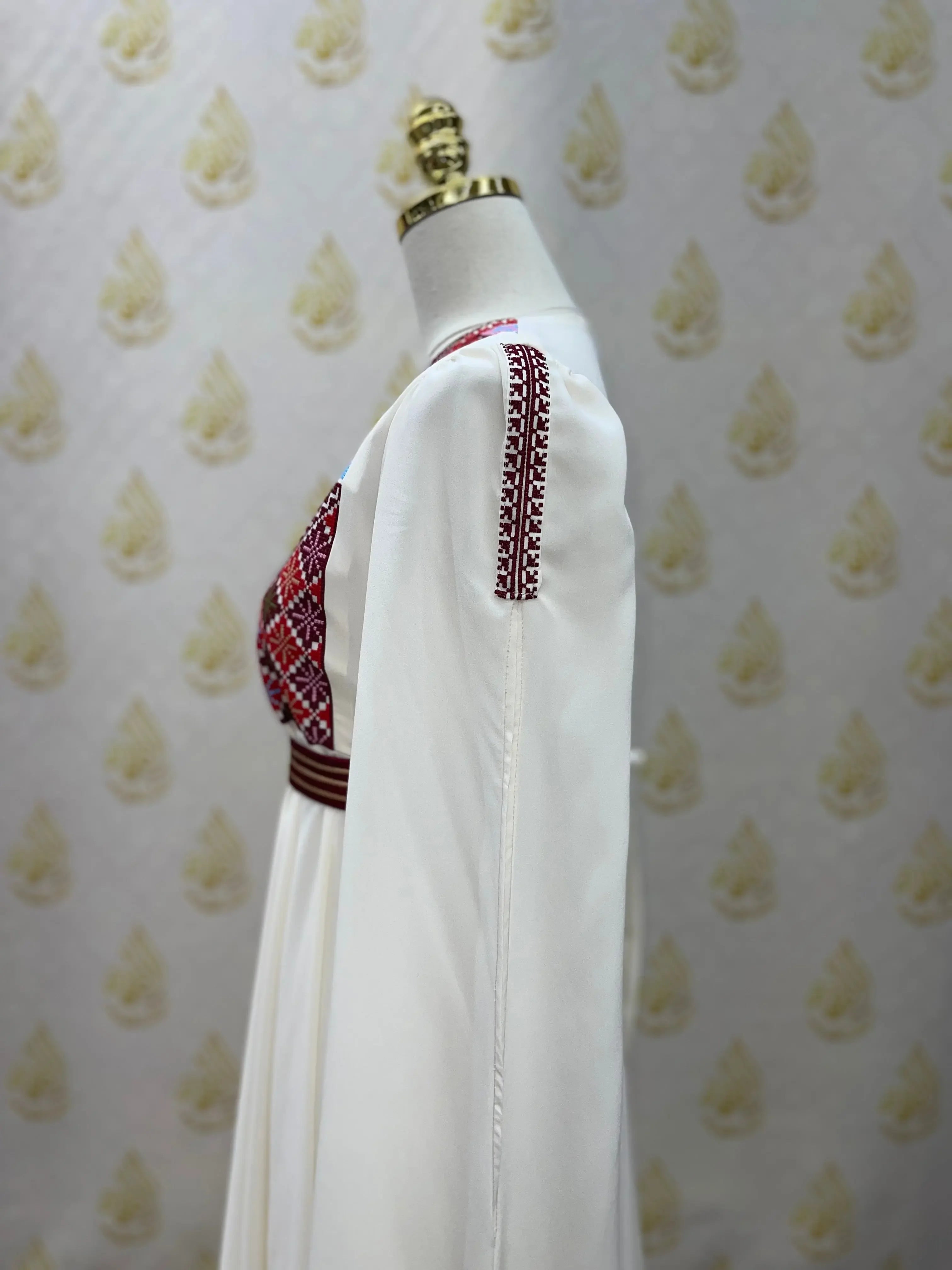 White Palestinian girls embroidered dress with red and black traditional embroidery on a mannequin