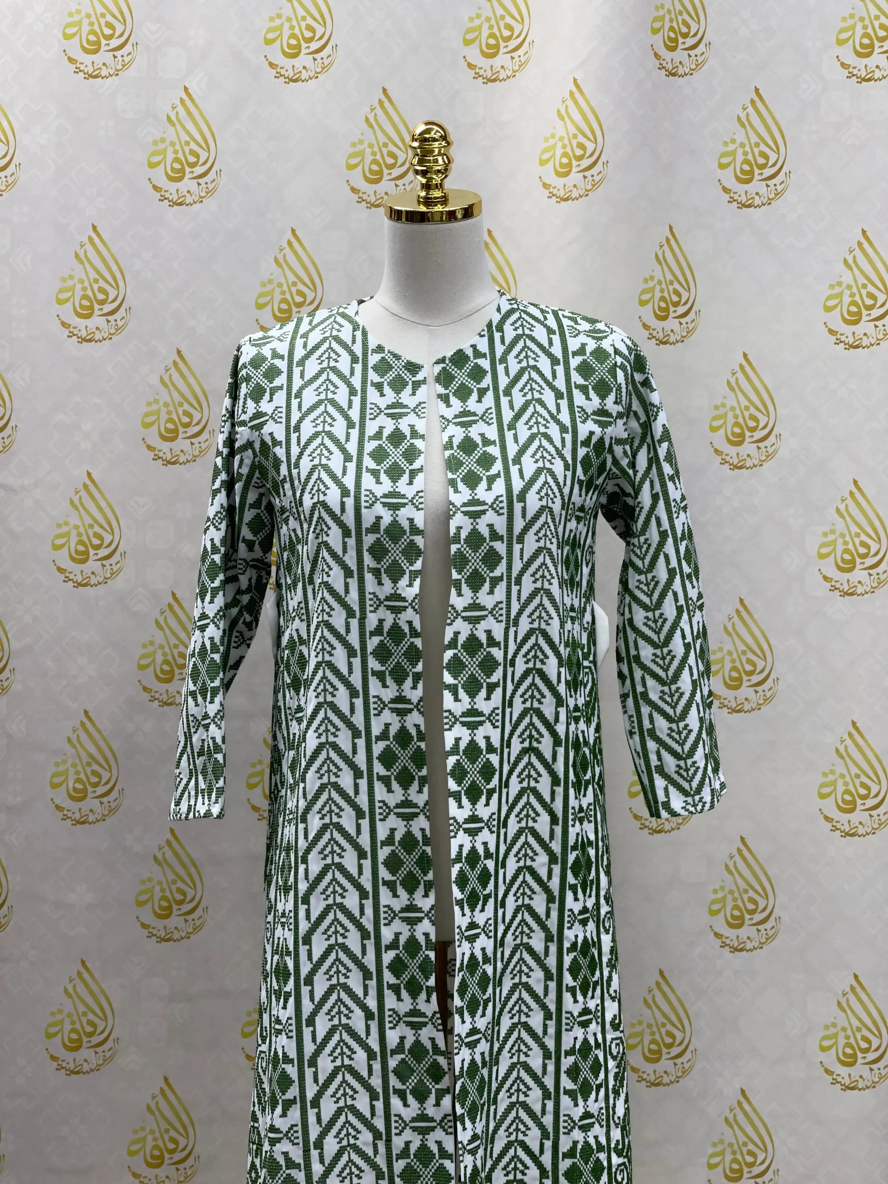Palestinian Elegance embroidered cardigan for kids with green geometric traditional patterns on white fabric