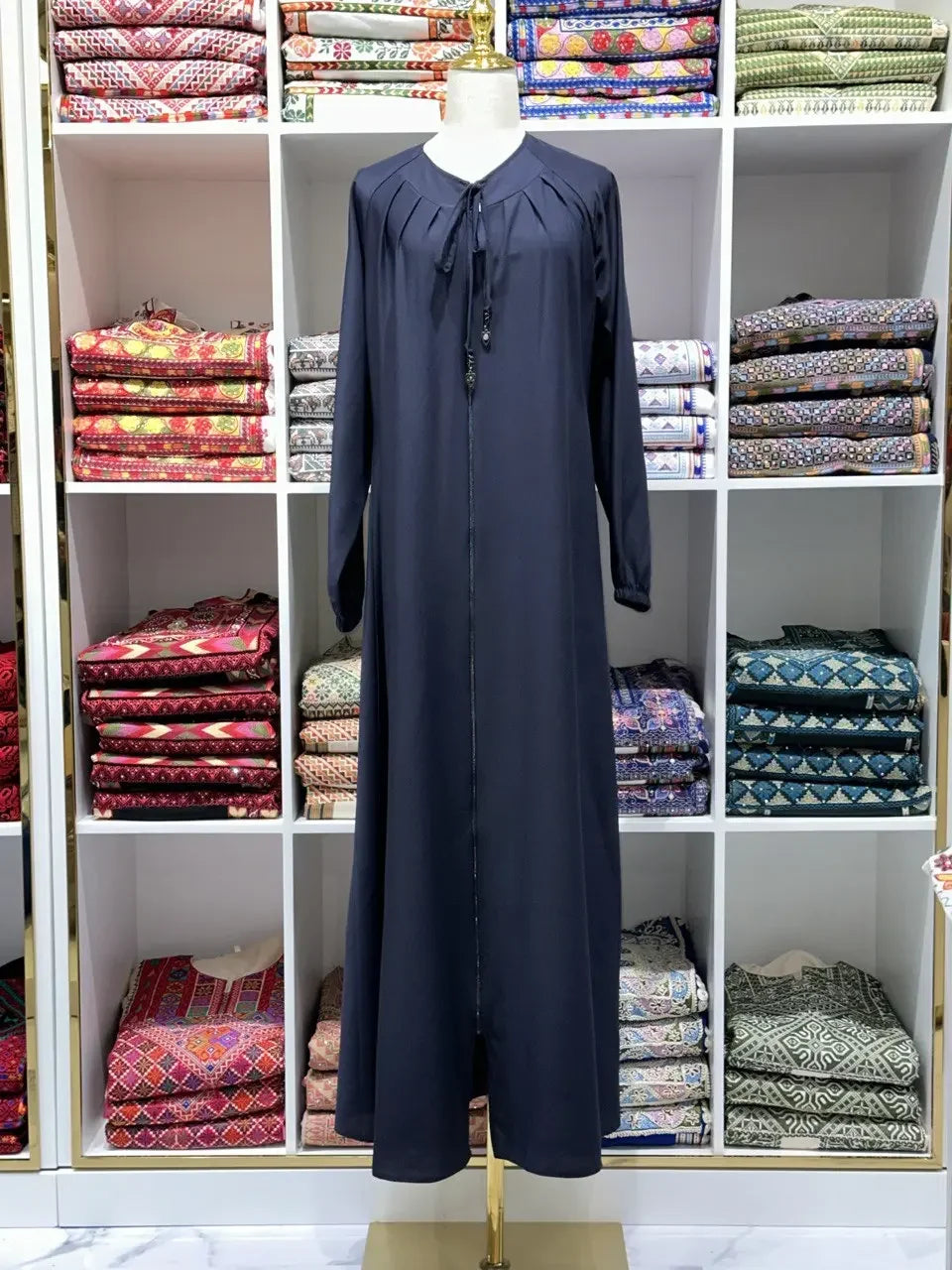 Palestinian Elegance navy umra abaya for women displayed on mannequin with patterned fabrics in background