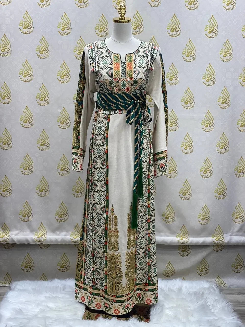 Embroidered Palestinian thobe with intricate traditional designs and a striped waist belt displayed on a mannequin