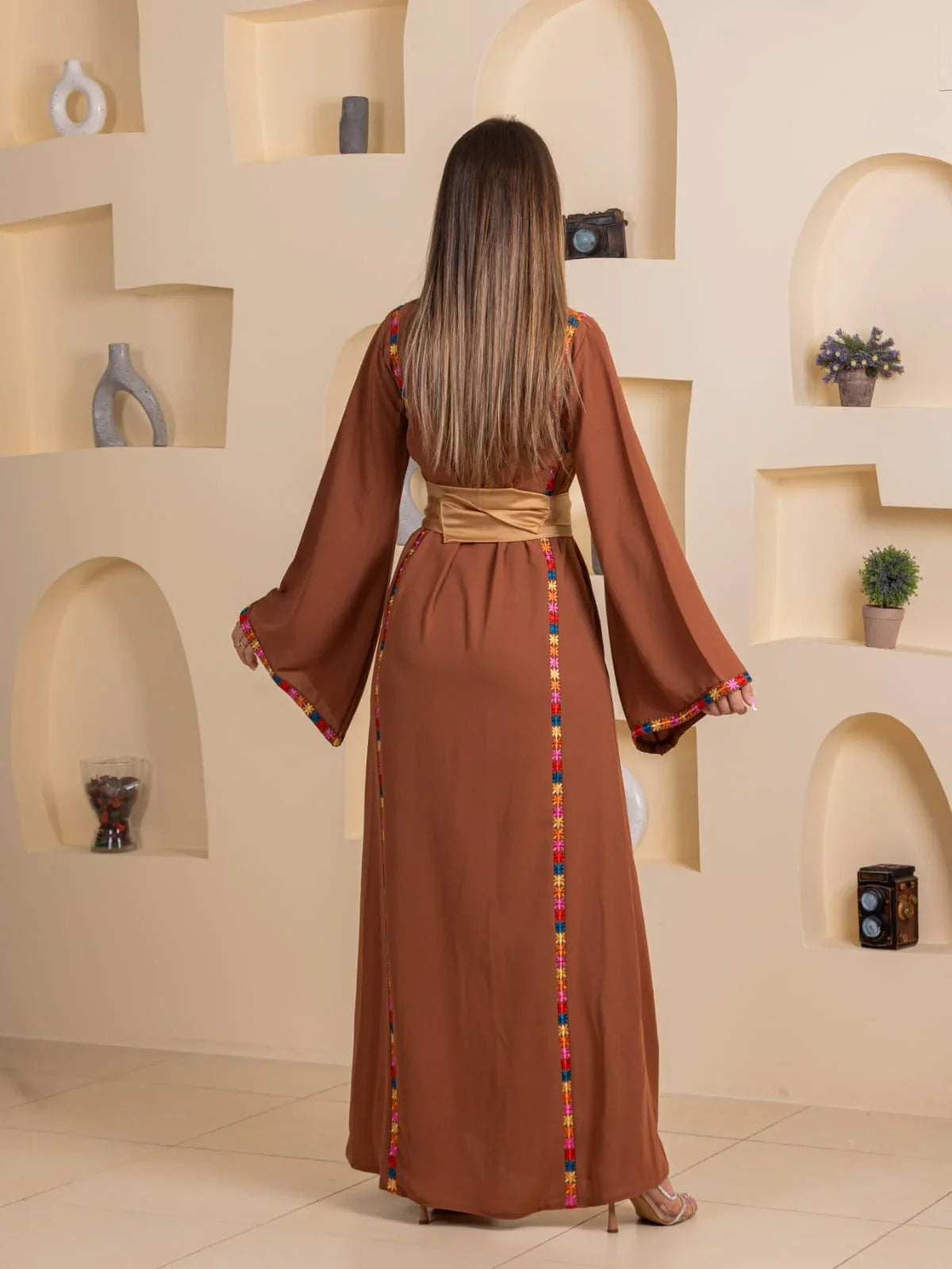 Back view Blossom Embroidered Thobe in brown with colorful embroidered trim wide sleeves and gold sash belt