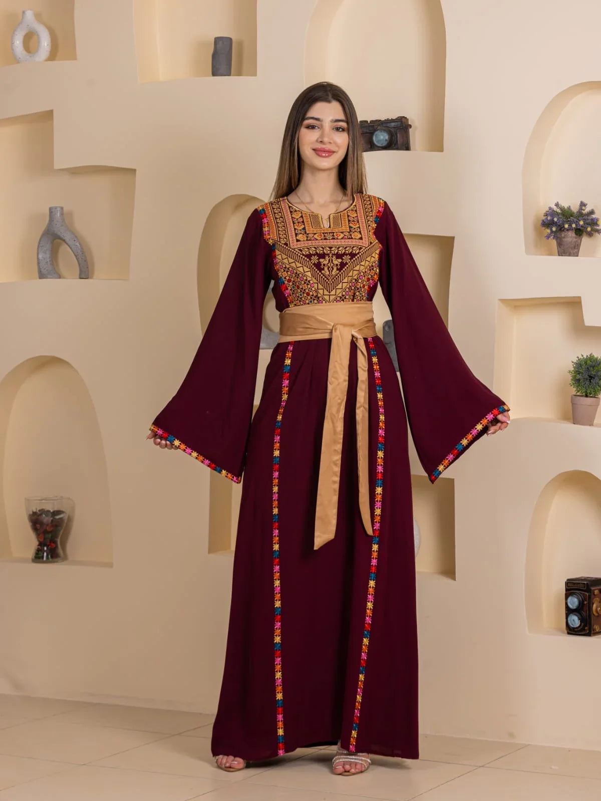 Woman wearing maroon Blossom Embroidered Thobe with gold sash and traditional Palestinian embroidery details