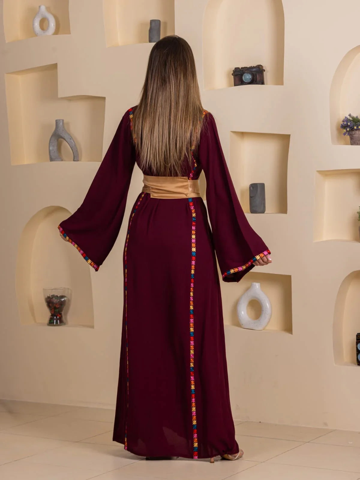 Back view of Blossom Embroidered Thobe in burgundy with colorful side embroidery and gold sash belt