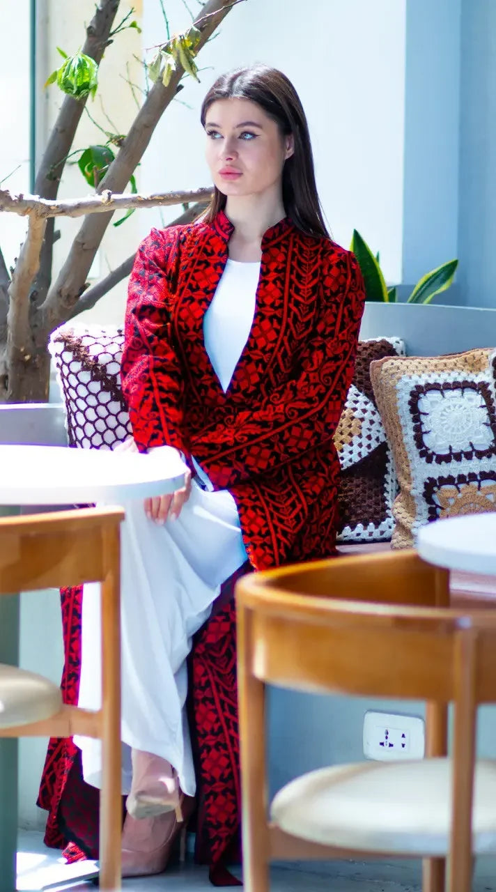 Palestinian Elegance embroidered long cardigan with intricate red and black patterns worn over a white dress