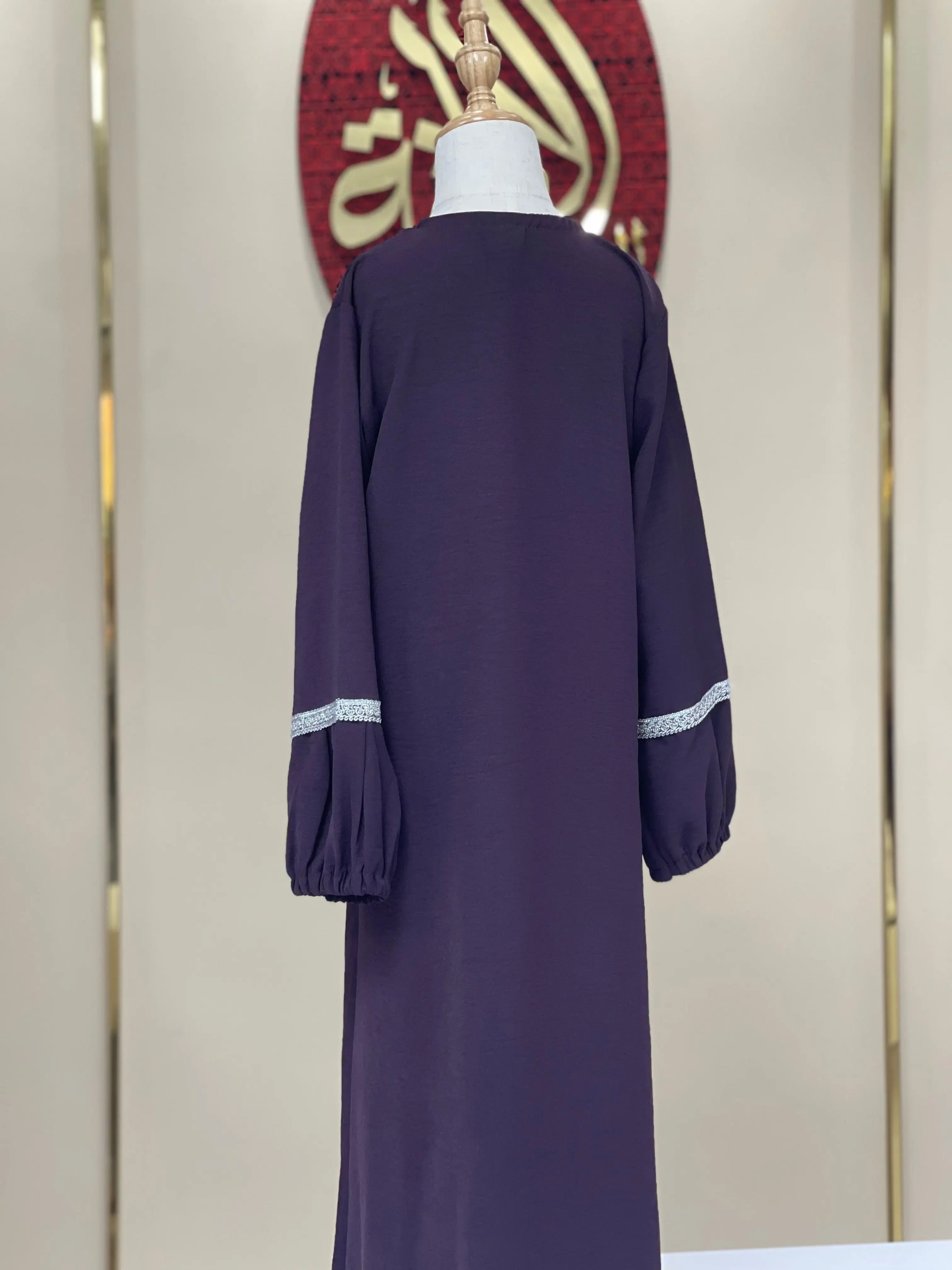 Back view of a girls embroidered abaya in dark purple with long sleeves and white lace trim from Palestinian Elegance