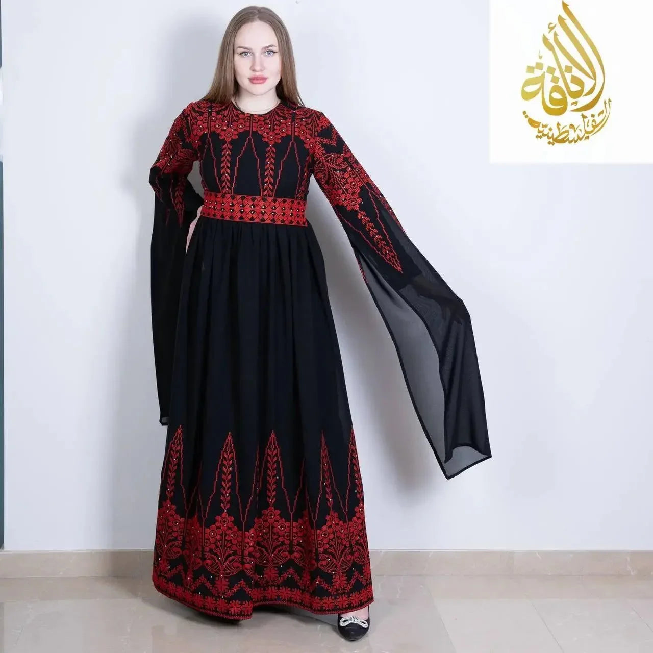 Palestinian embroidered dress by Palestinian Elegance featuring black fabric with intricate red embroidery and flowing long sleeves