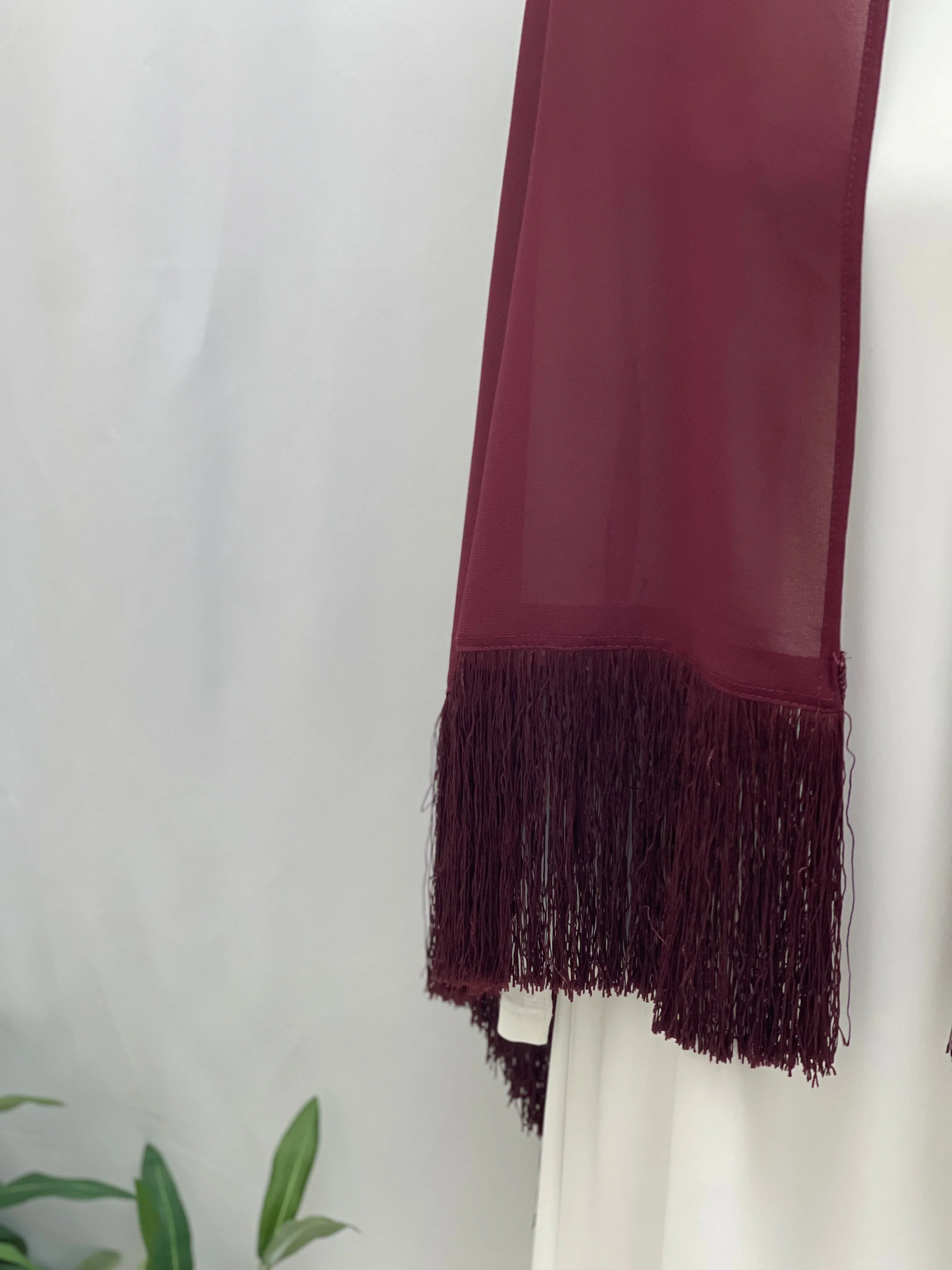 Dark Maroon Khirka With Tassel draped over white dress showing long fringe hem by Palestinian Elegance