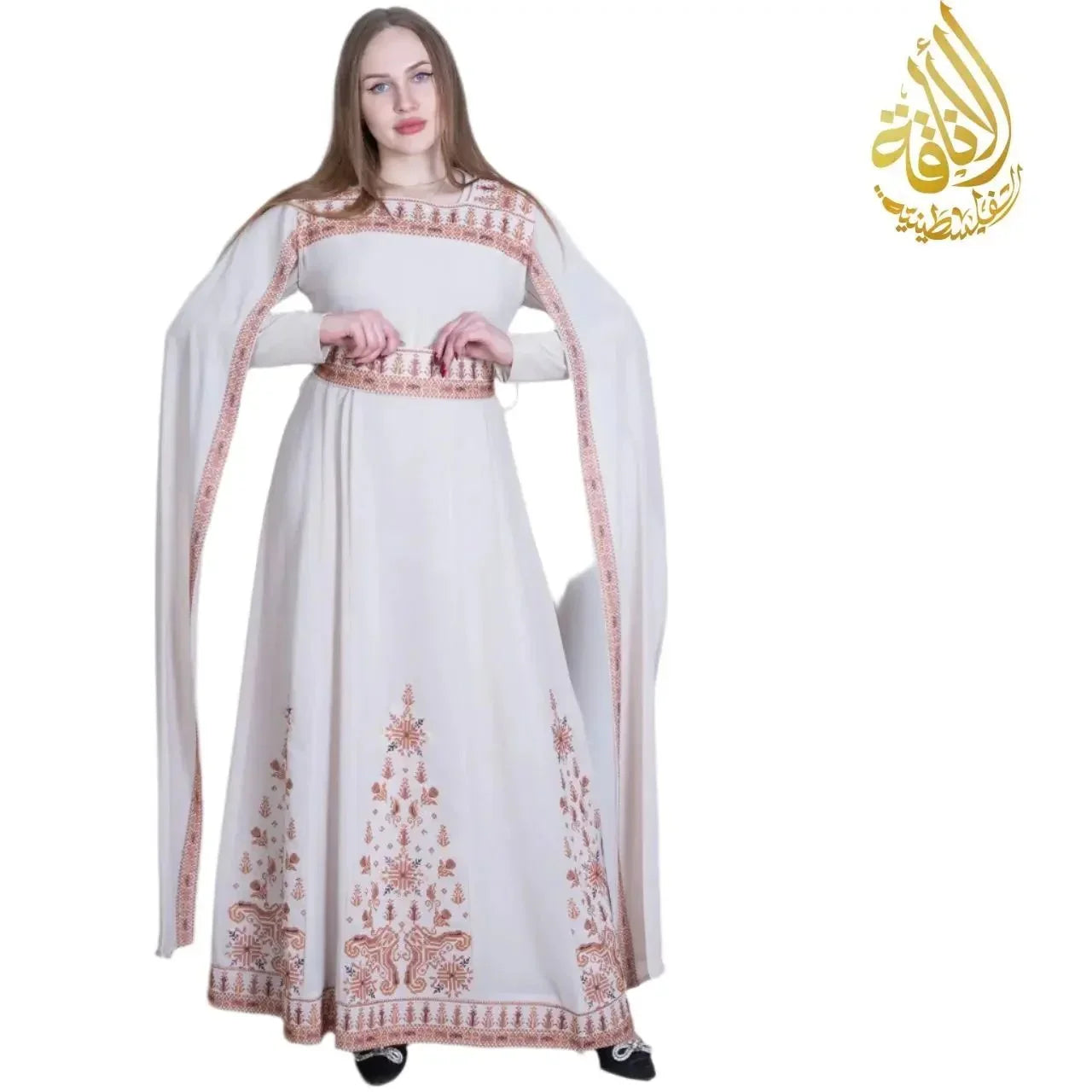 Woman wearing an embroidered Palestinian dress in white with intricate brown embroidery from Palestinian Elegance