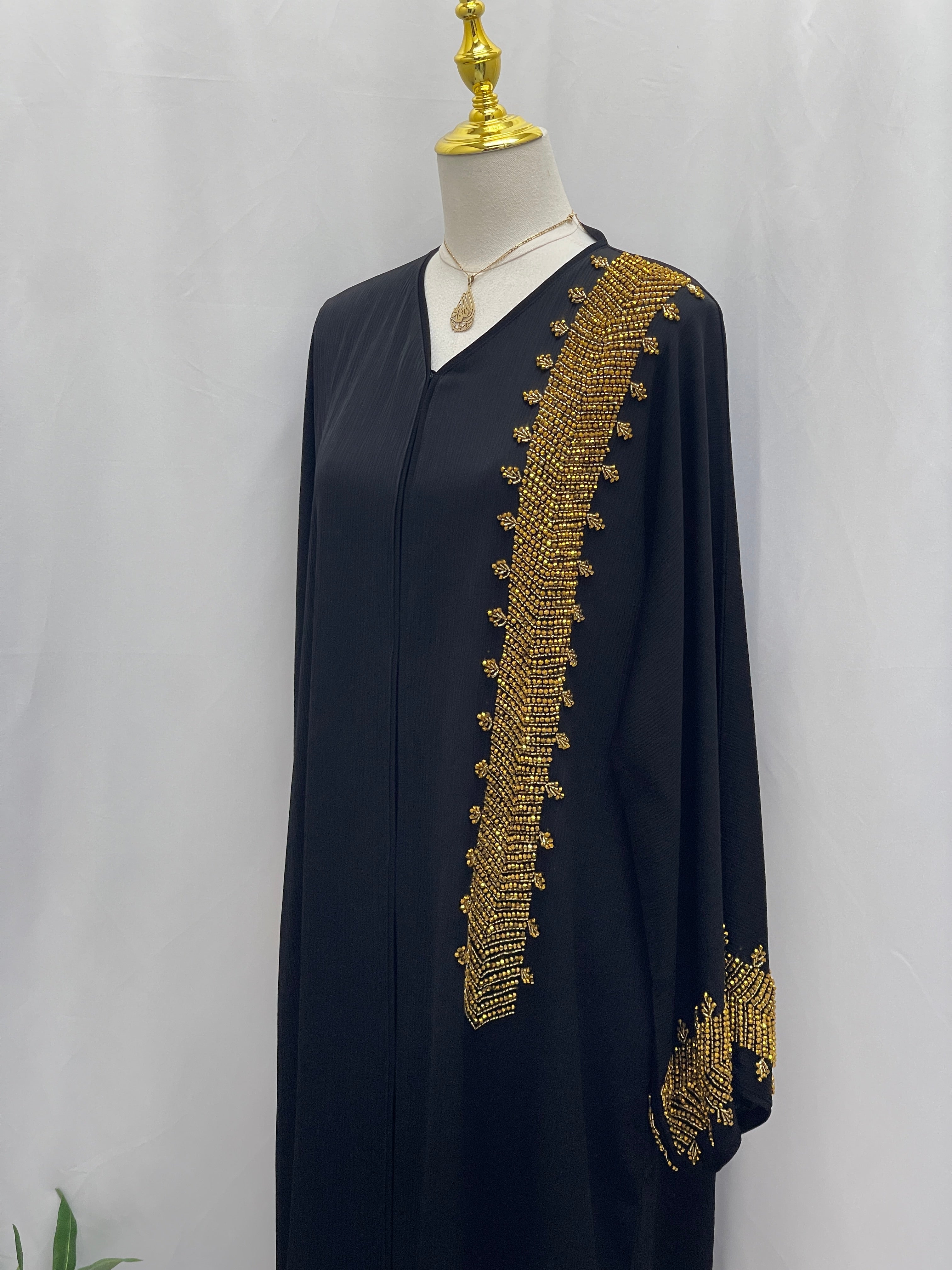 Palestinian Luxury Modest Fashion Abaya in black with intricate gold embroidery on sleeve and front