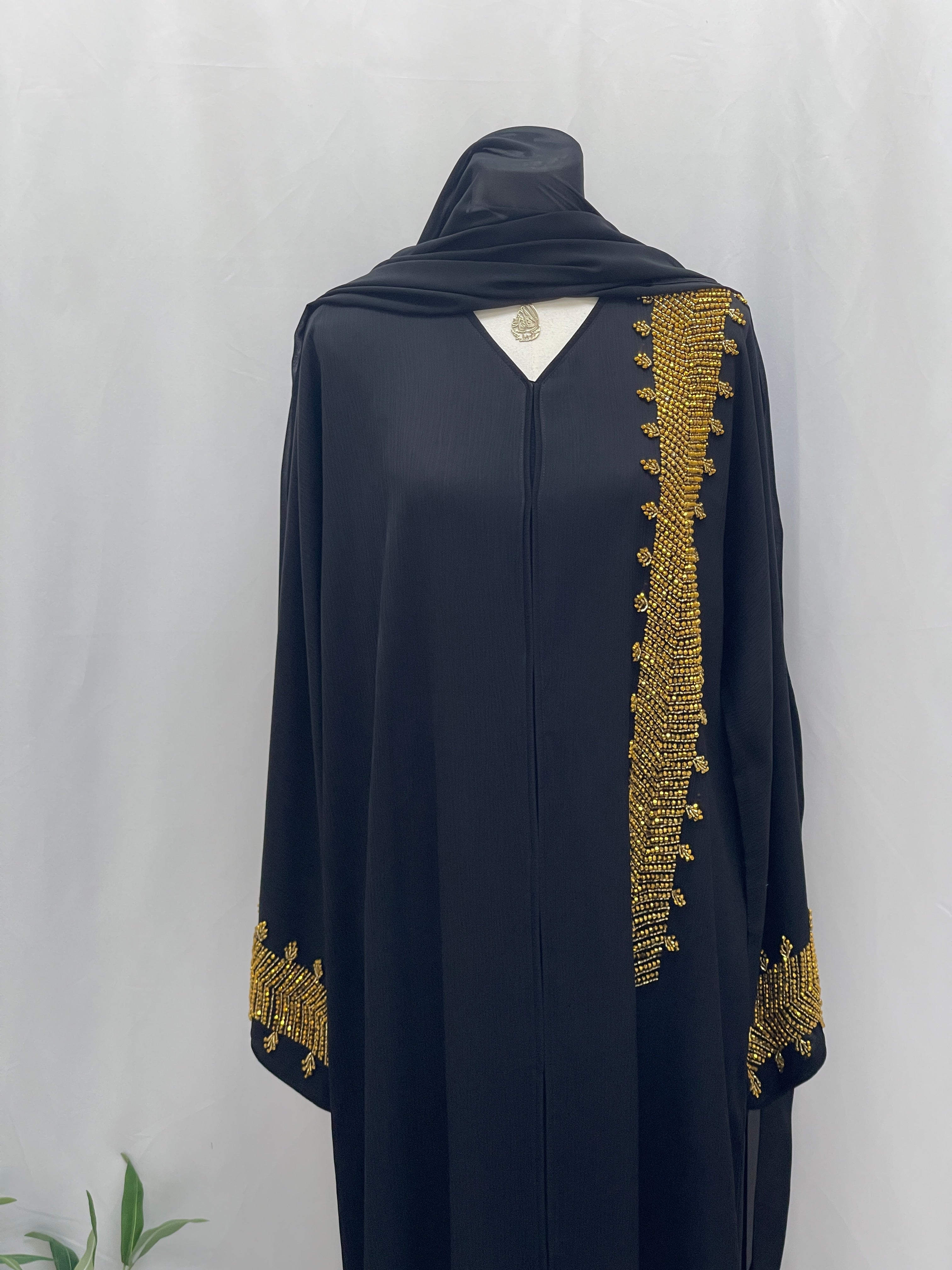 Palestinian Luxury Modest Fashion Abaya in black with intricate gold embroidery on sleeve cuffs and front panel