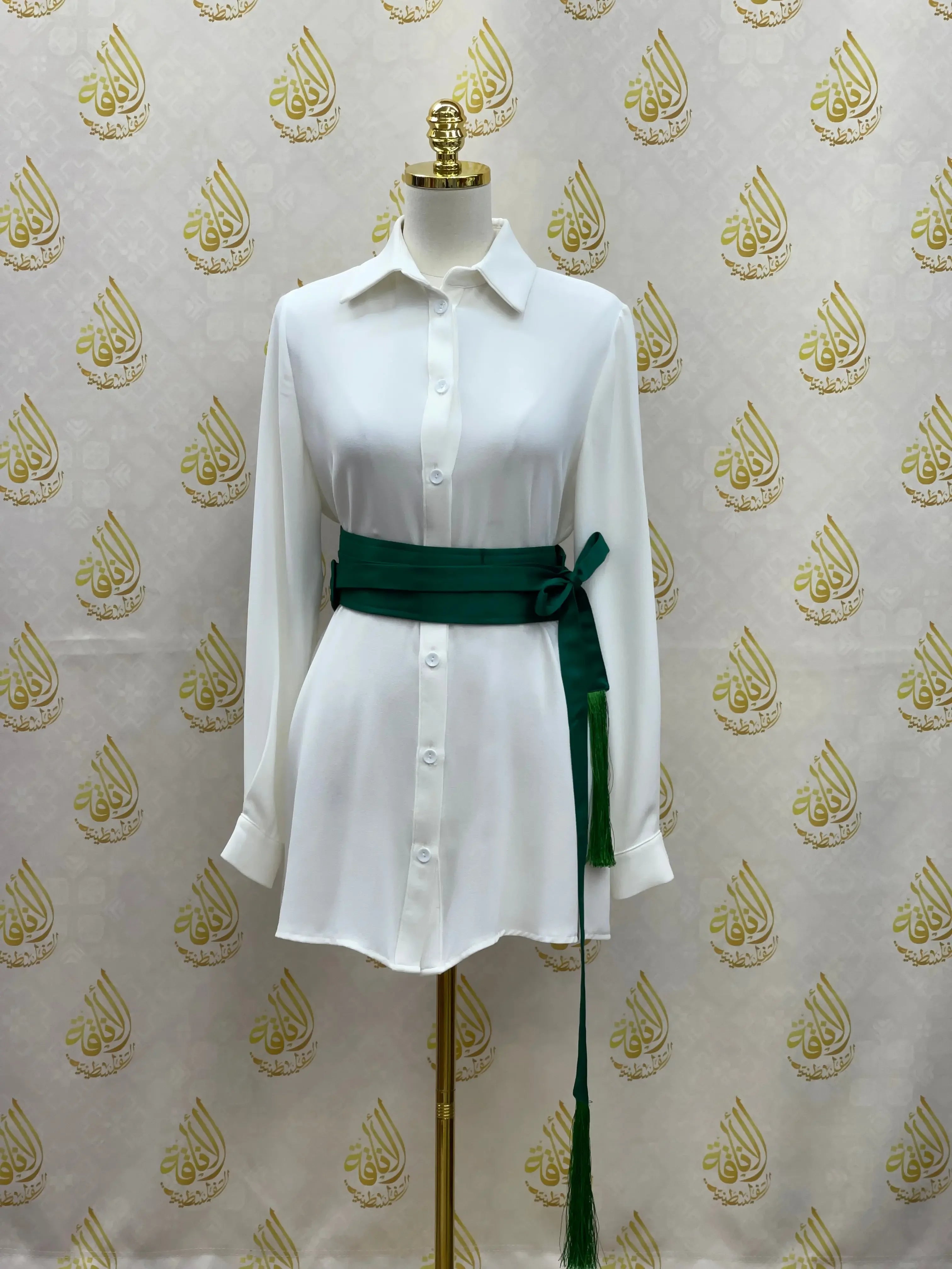 Luxury satin belt for dresses in dark green wrapped around white button-down dress on mannequin