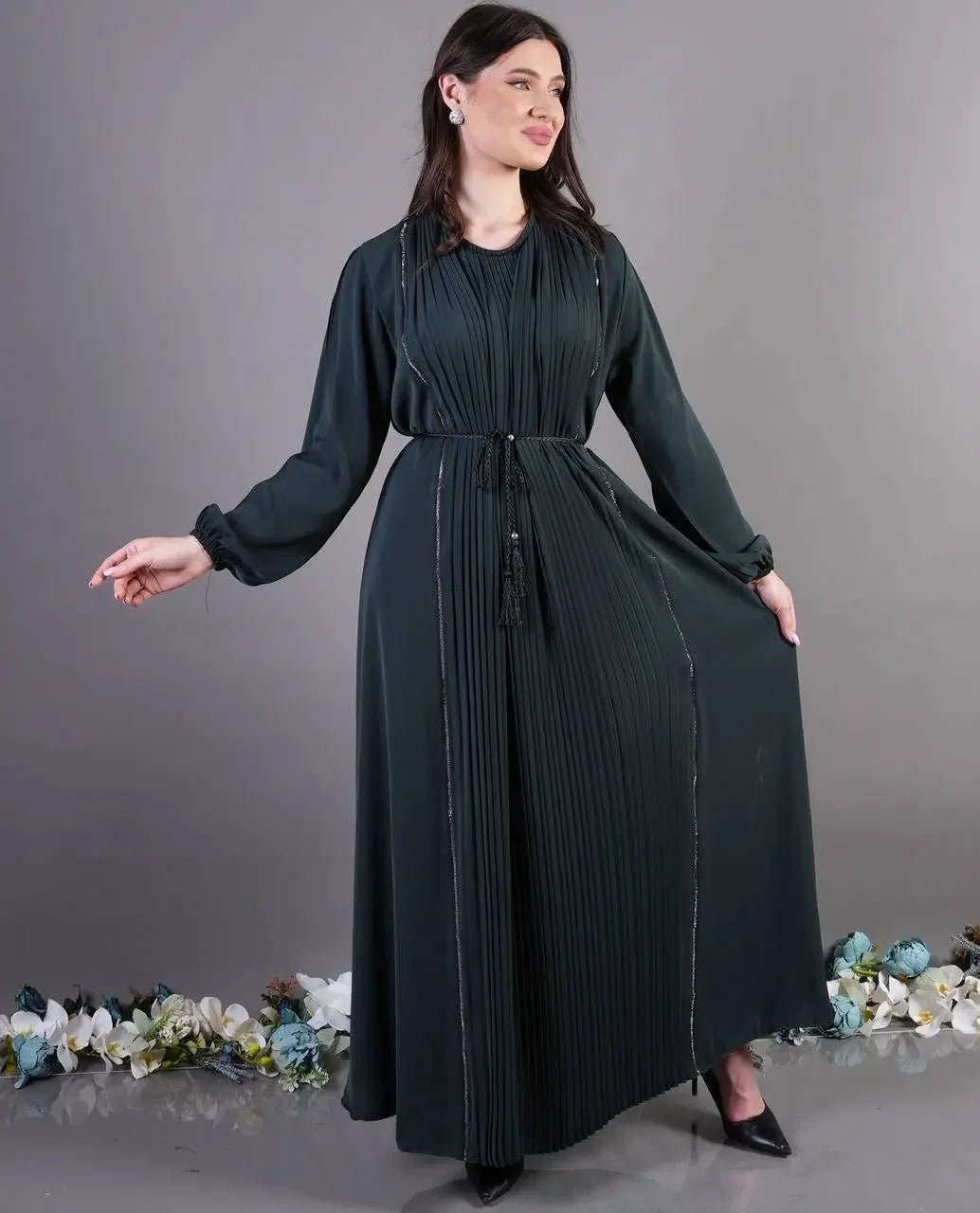 Palestinian Elegance black pleated abaya dress with long sleeves and tie waist worn by model
