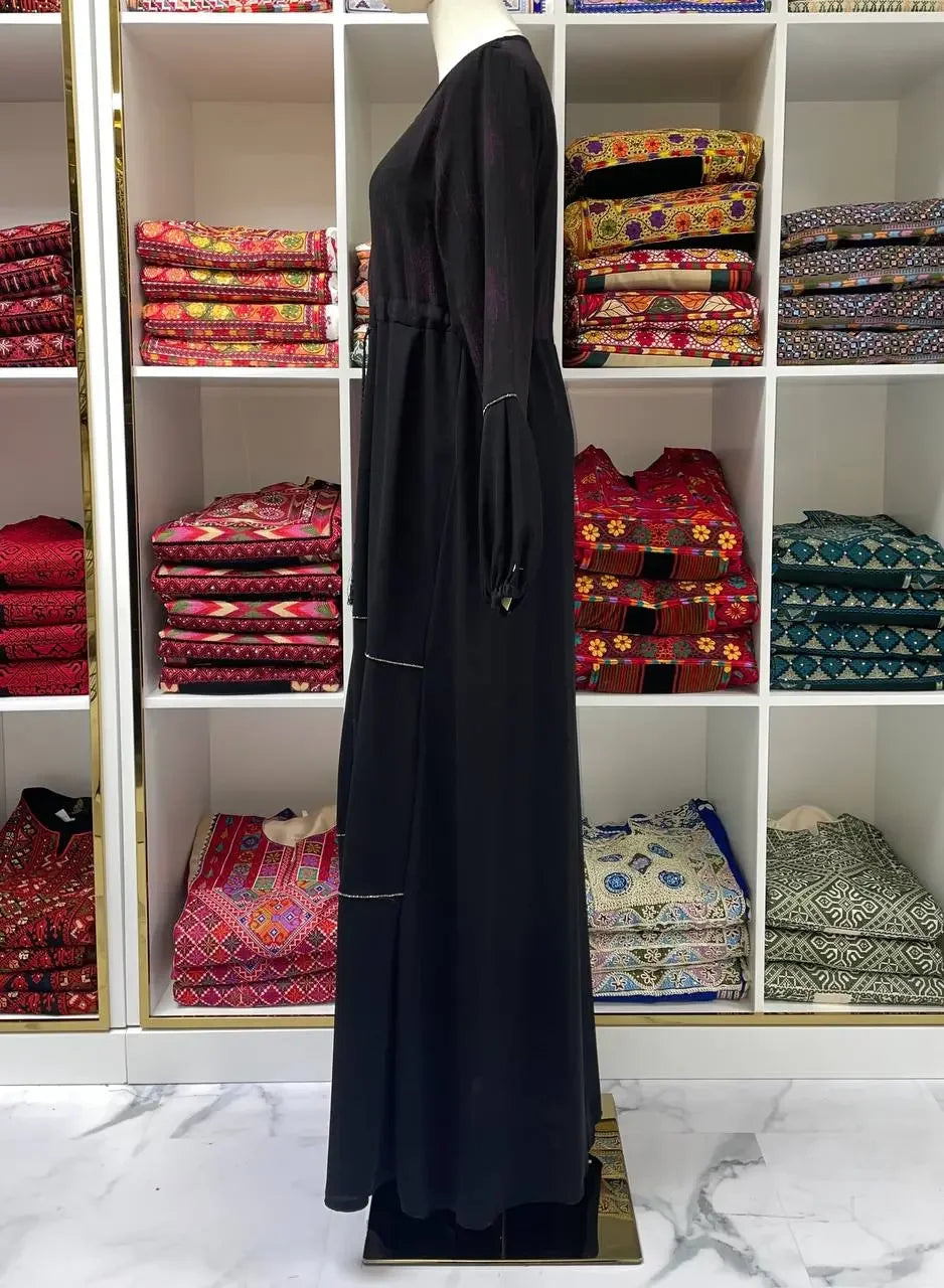 Palestinian Elegance modern abaya dress for women in black displayed on mannequin with traditional fabric background