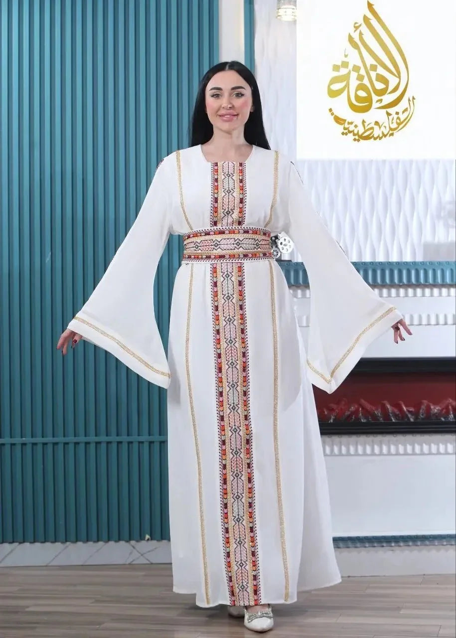 Woman wearing a white embroidered Palestinian kaftan with colorful detailed embroidery down the front and sleeves